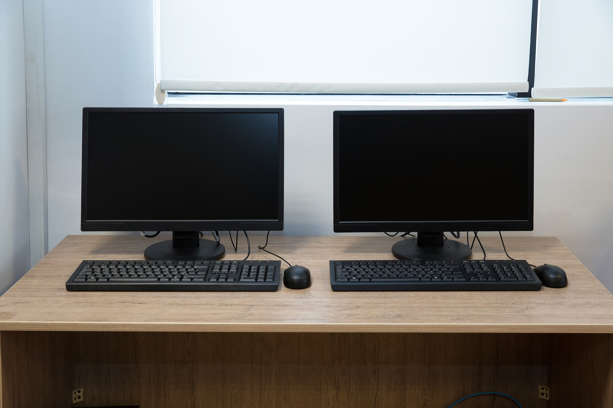 two computers and a desk . keyboard and mouse . two computer mon