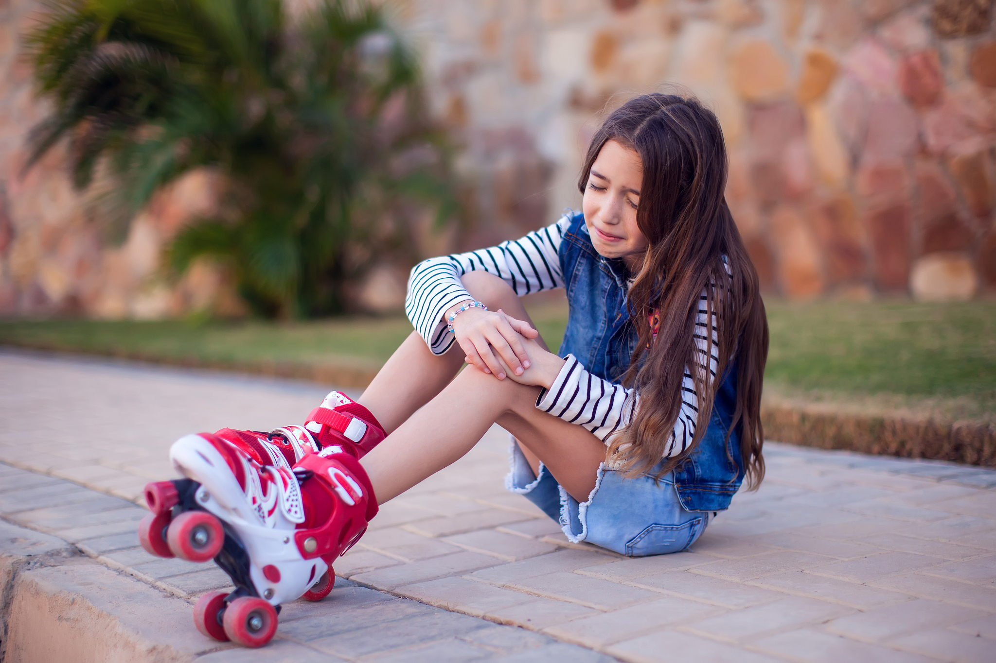 a kid girl on rollerskates fell down and feels pain. children, a