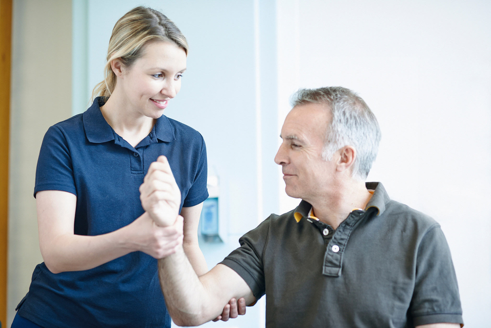 physiotherapist helping man to do arm exercise