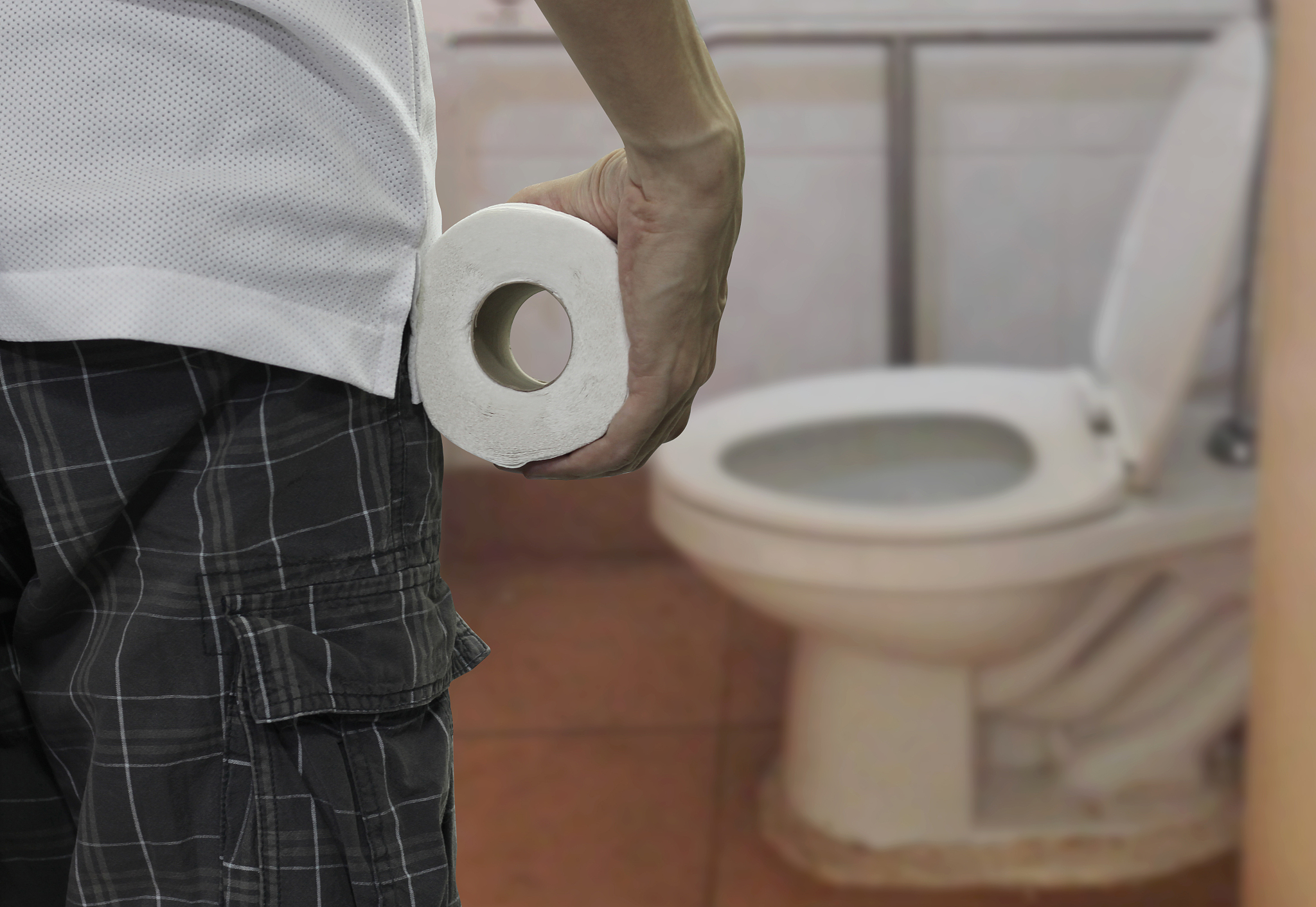 hand holding toilet paper roll and entering the toilet.