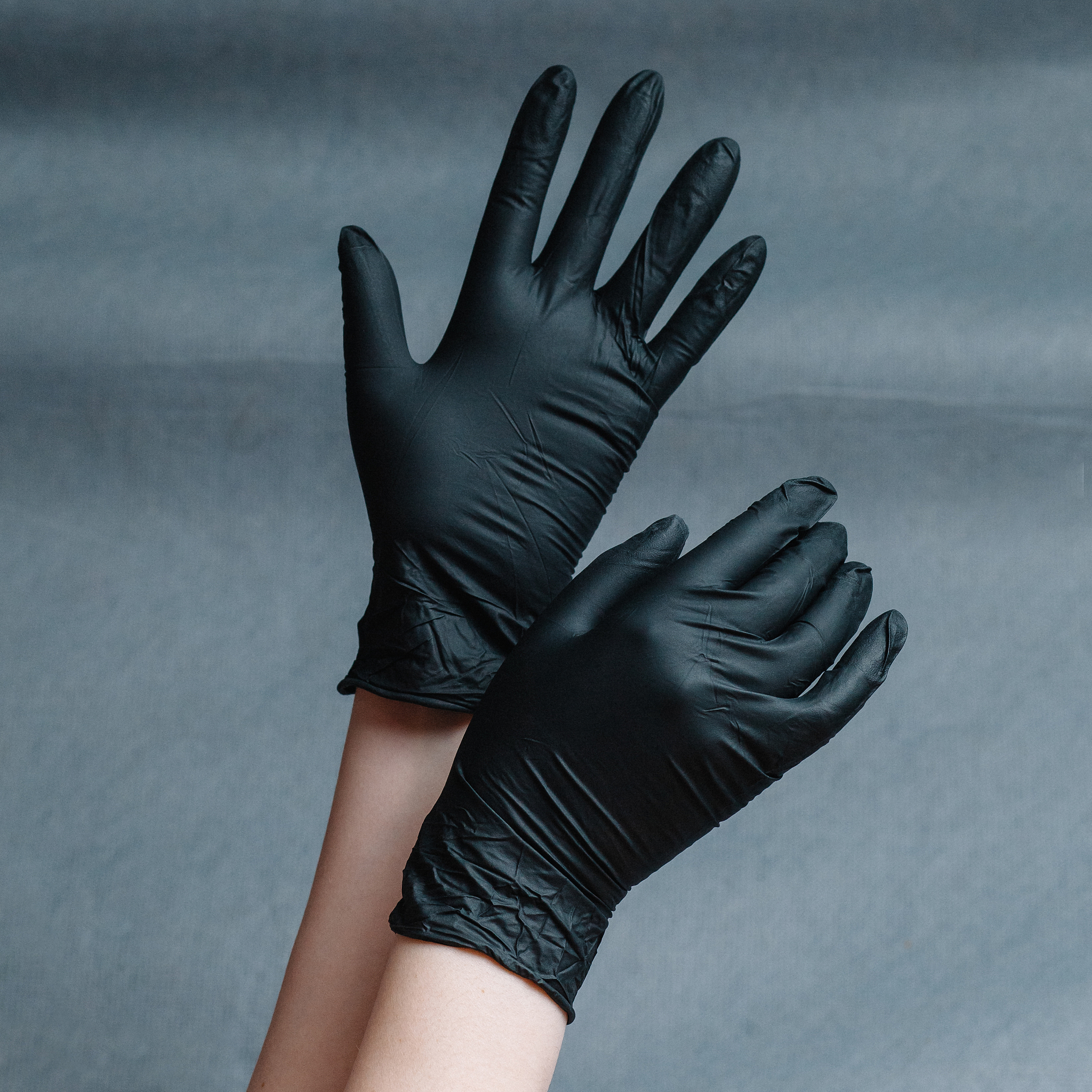 hands in nitrile gloves of gold color on a gray background with 