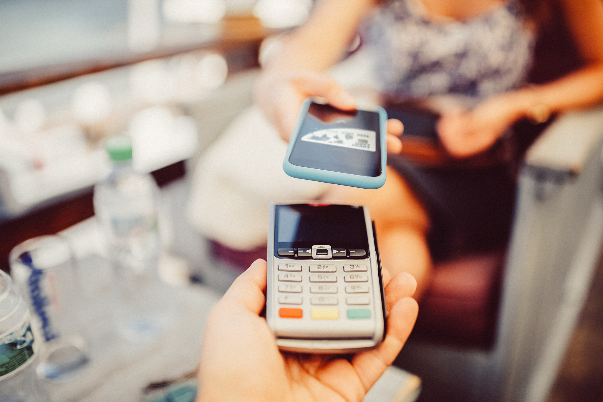 woman at cafe paying contactless with smartphone