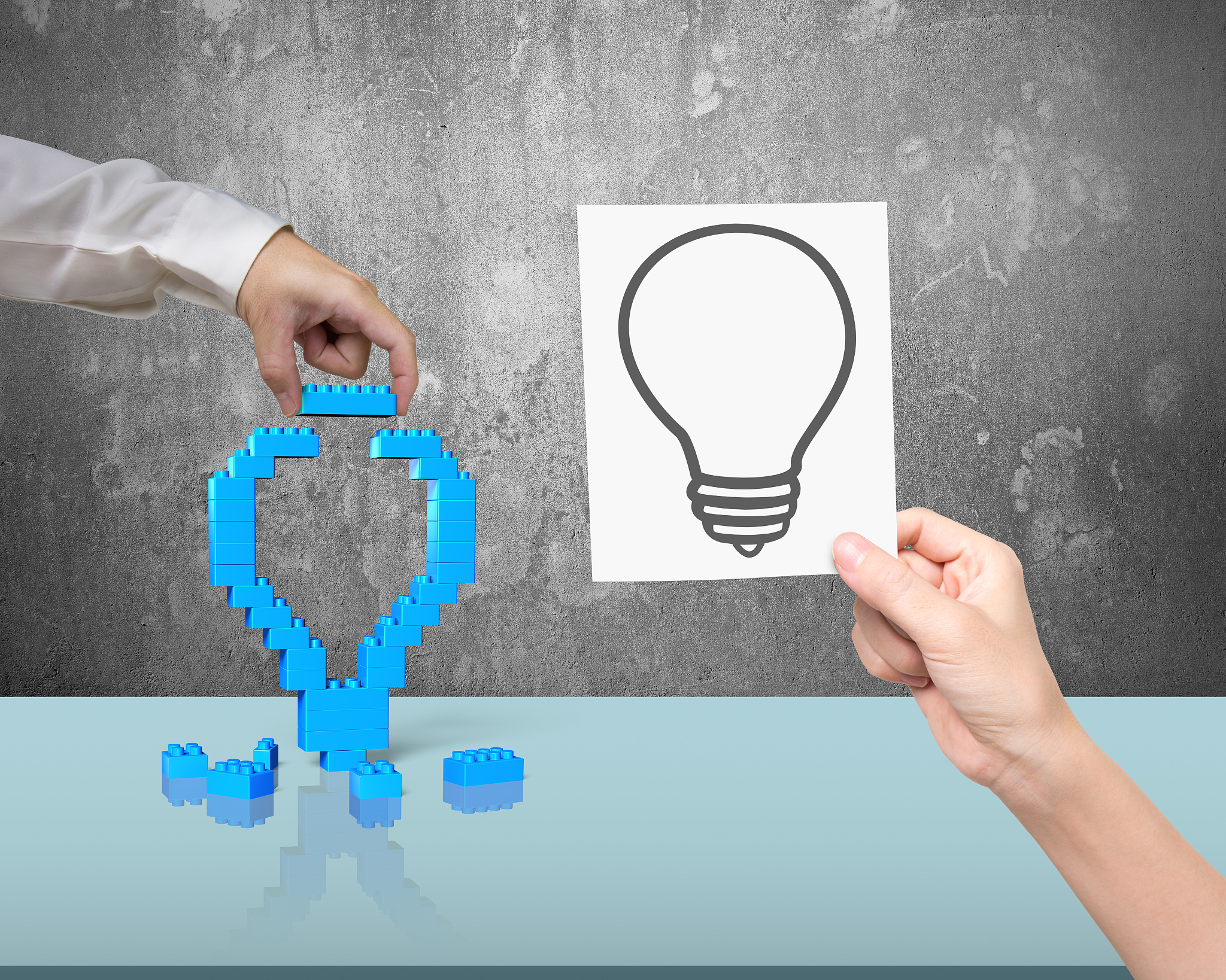 one hand building stack blocks lightbulb the other holding bluep