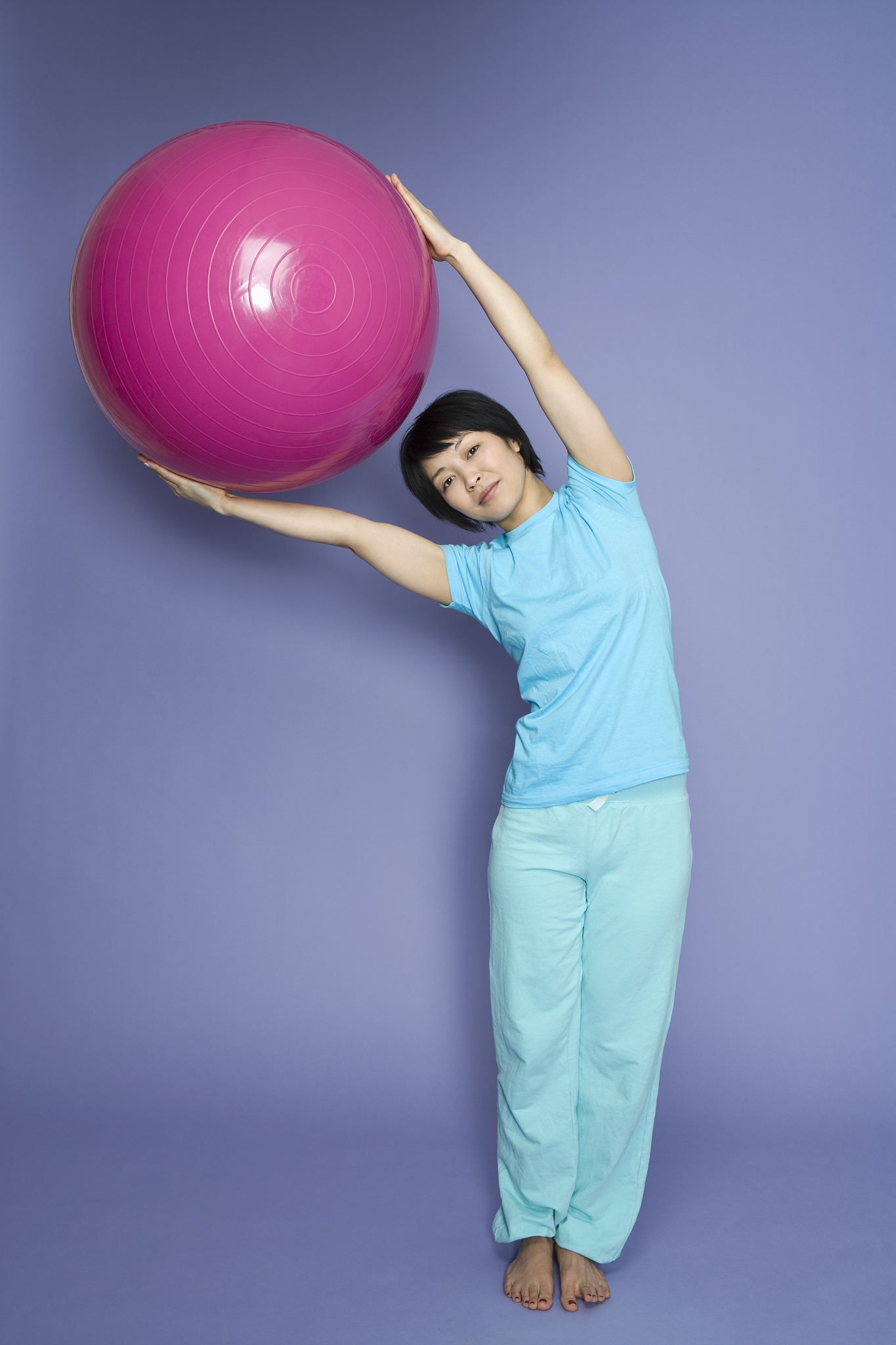 a woman standing and holding a fitness ball