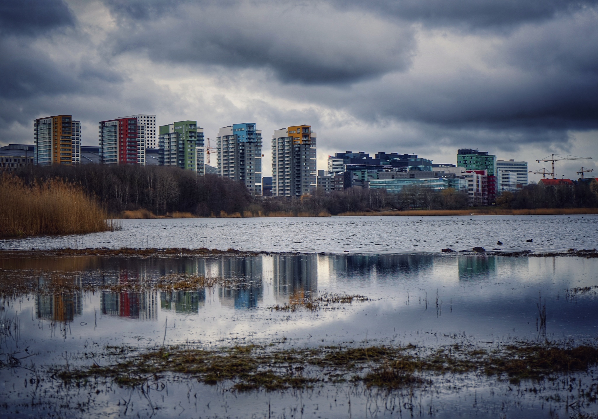 reflection of buildings in lake against cloudy sky