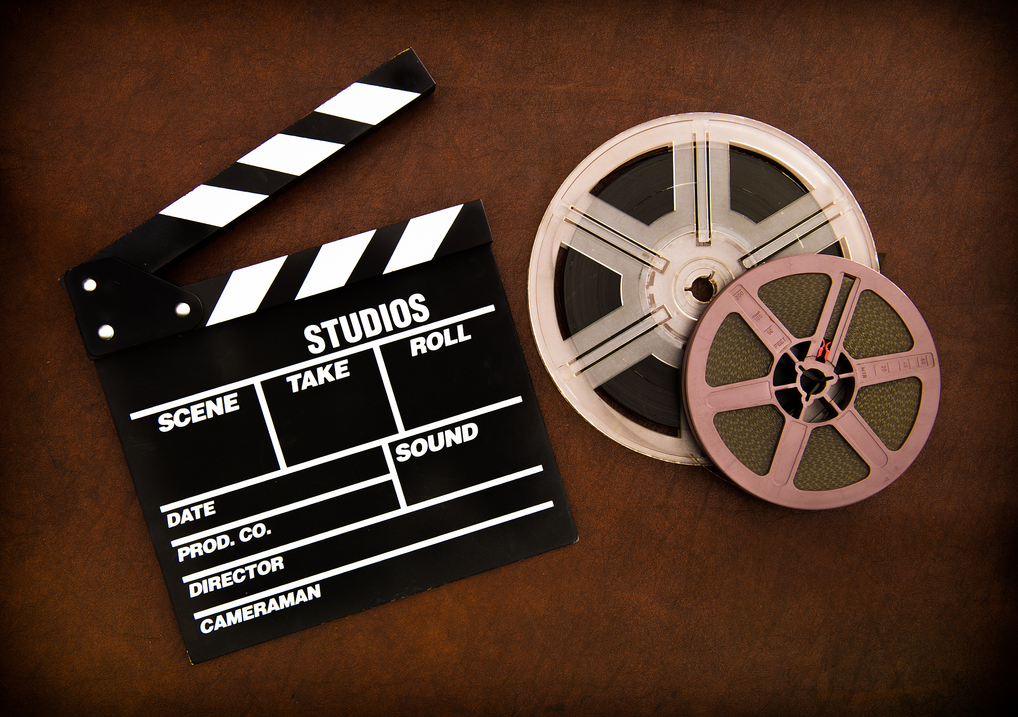 movie clapper board and film reels detail on wooden floor