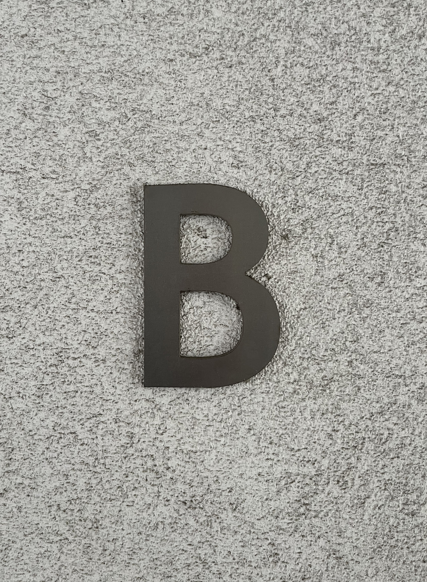 字母b安装在浅灰色纹理墙上,构成一幅具有强烈对比的