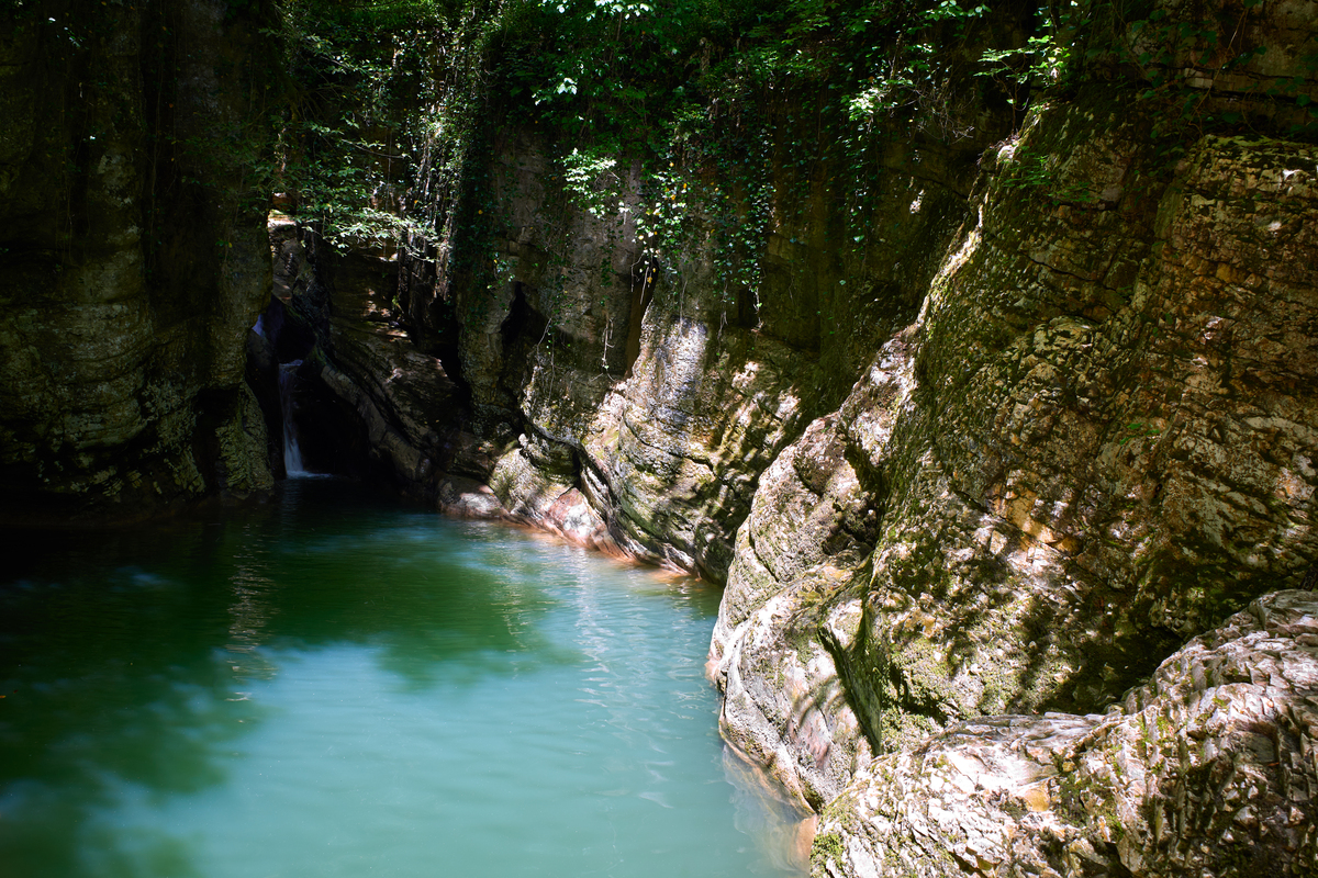 请用100字描述马岭河峡谷群山连绵苍翠欲滴蓝天白云山脚下草原青绿的场景
