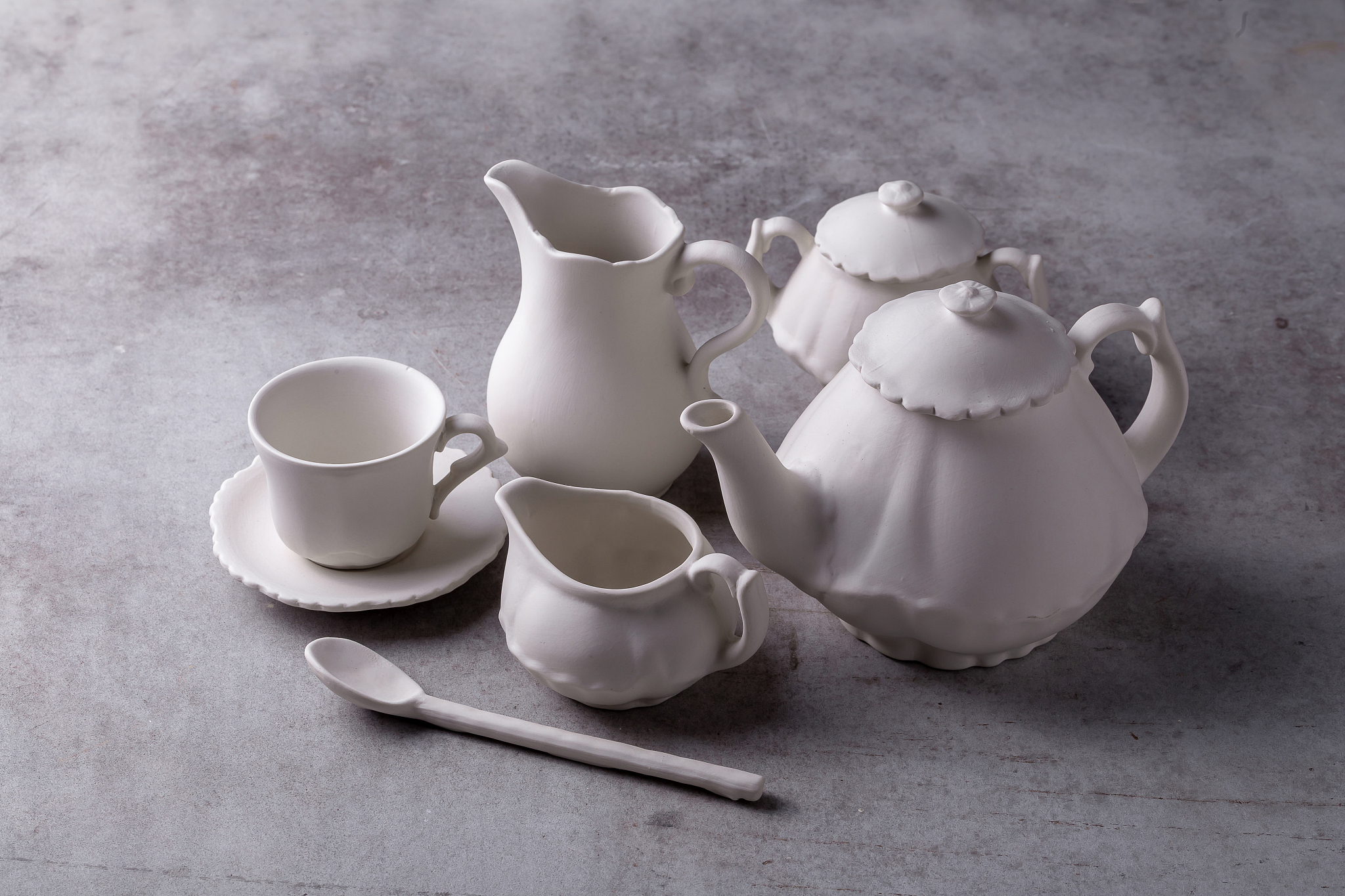 teapot creamer, cup and saucer on cement board