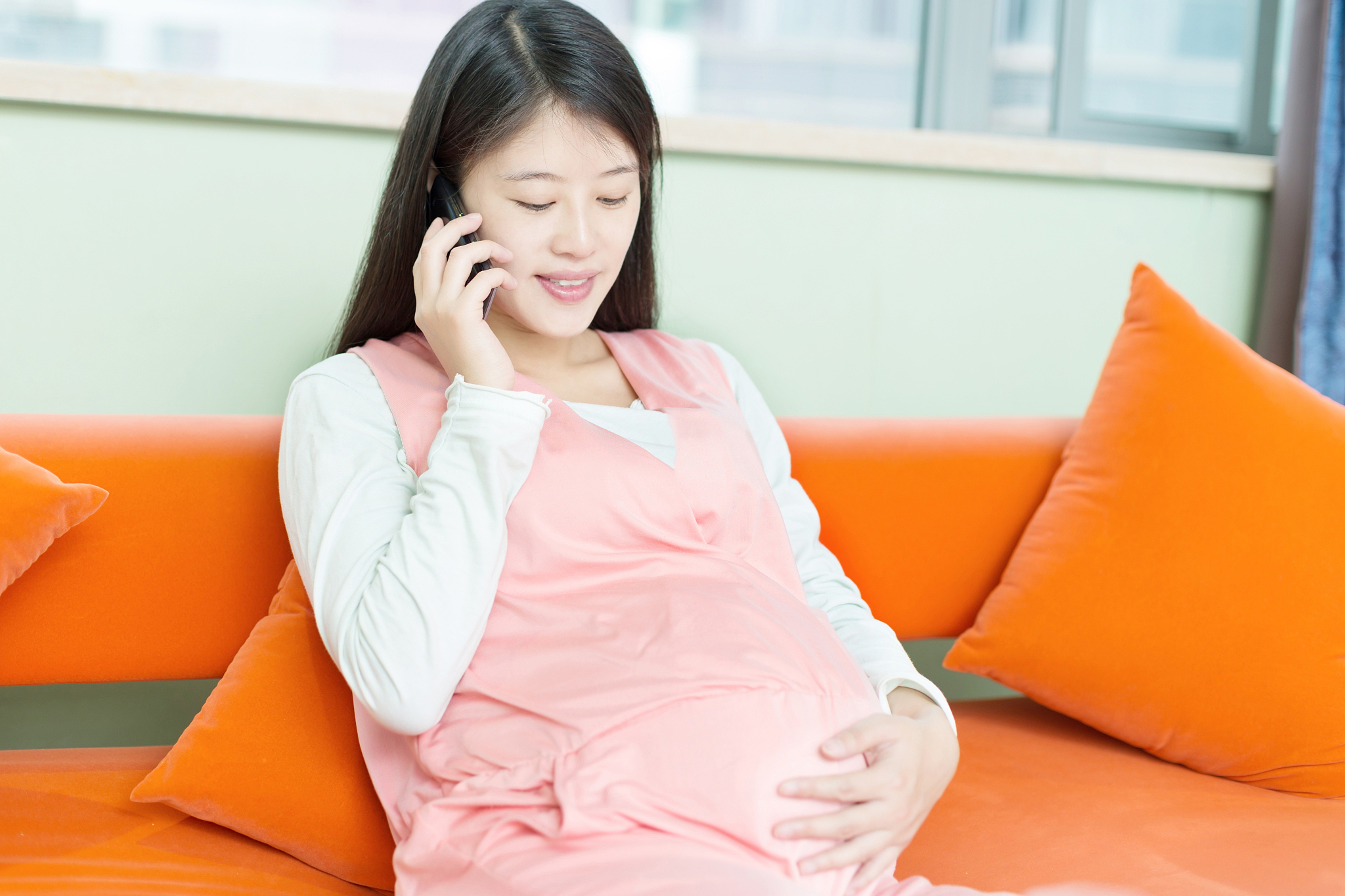 年轻美丽的孕妇坐在沙发上休息