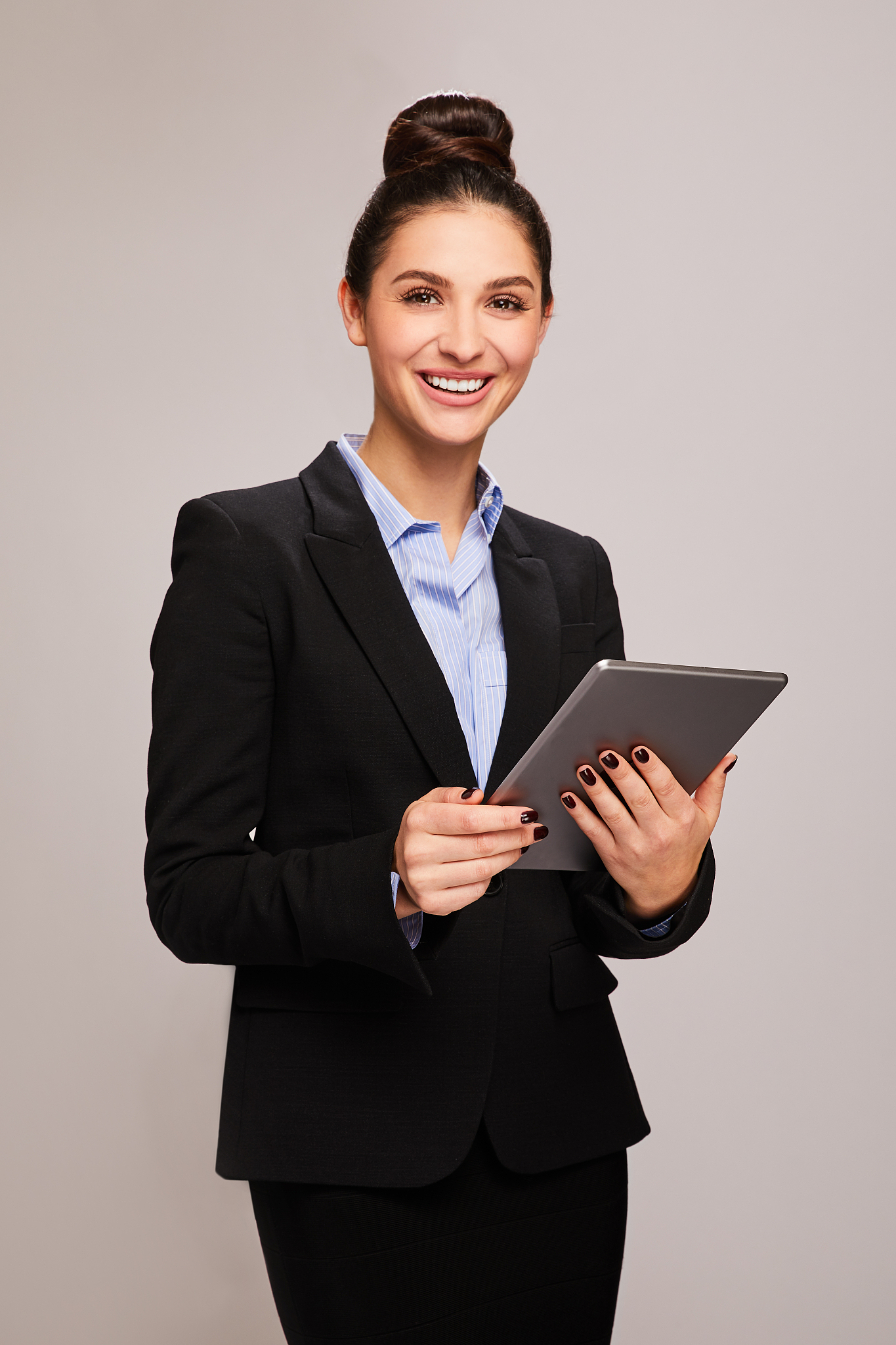 smiling businesswoman standing against a gray background using a