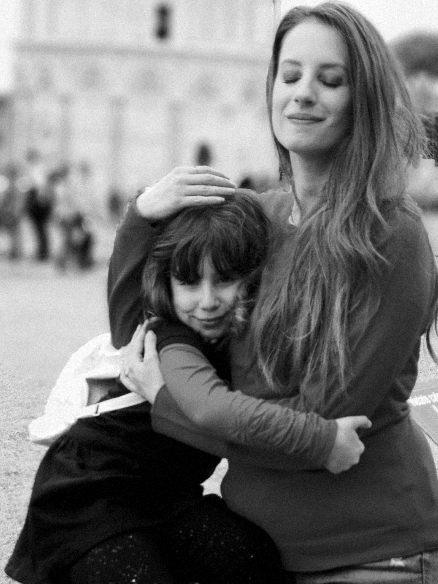 mother and daughter embracing in city