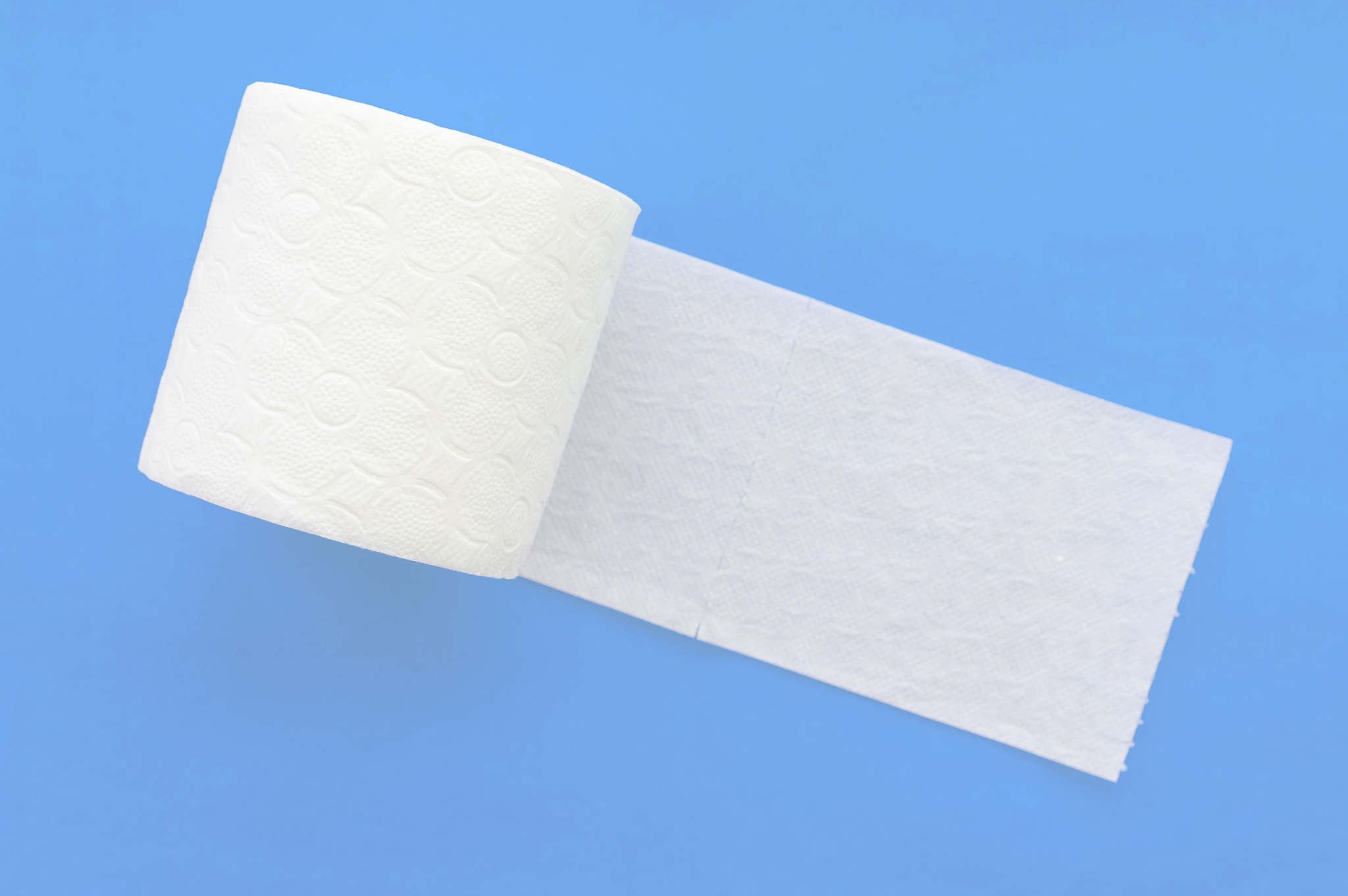 roll of white toilet paper on a blue background. close up.
