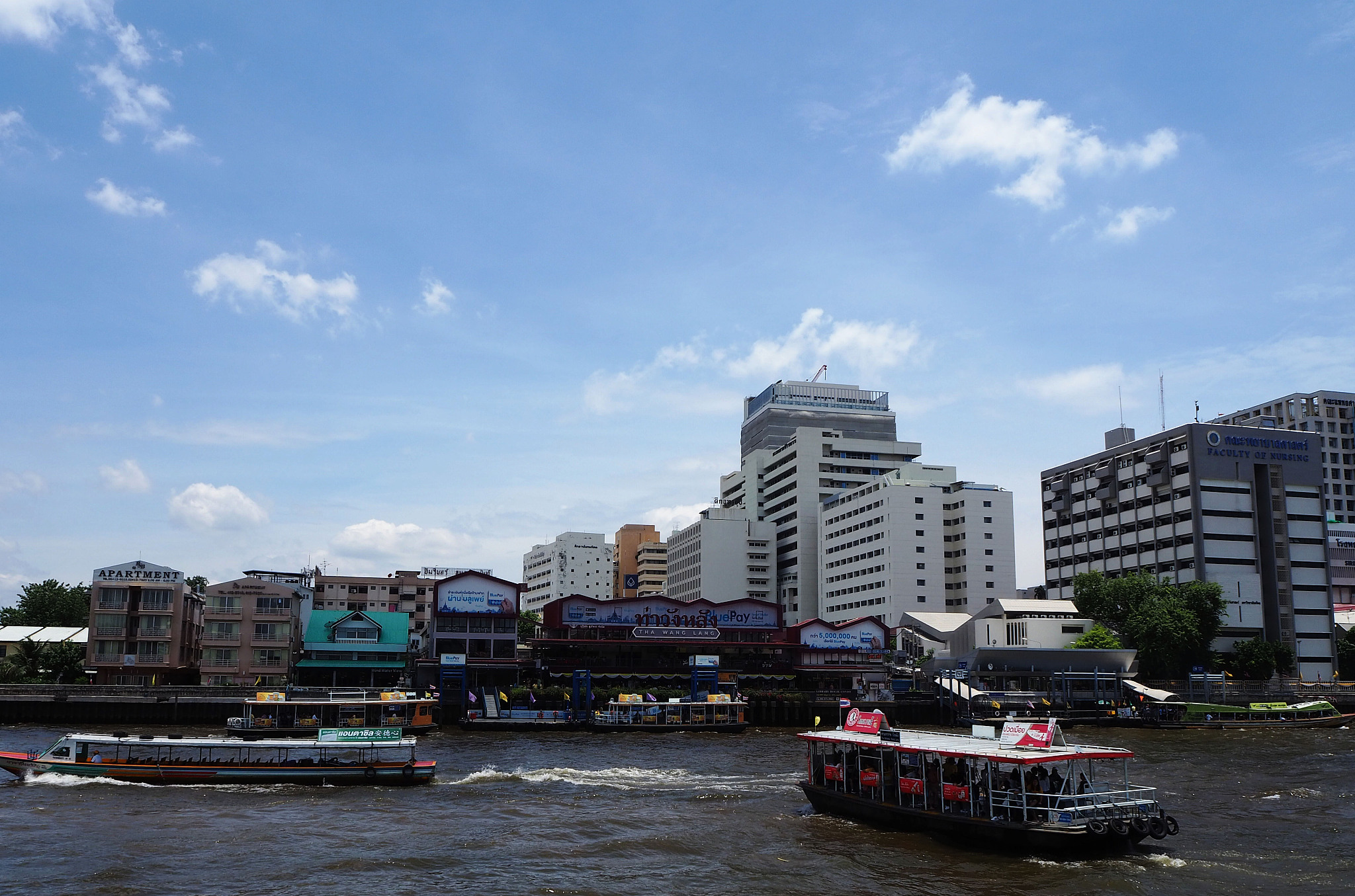 boats in river amidst buildings in city against sky