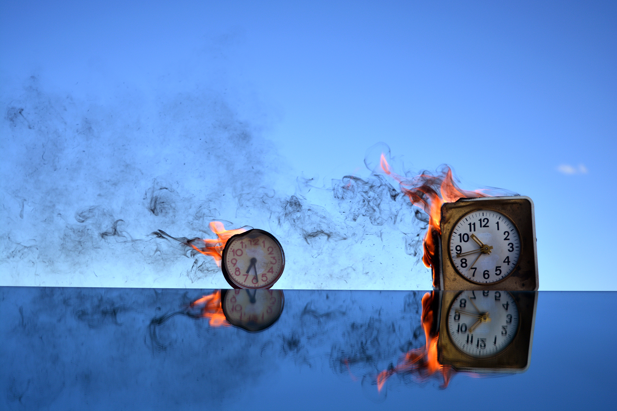 two antique clock burning in space on mirror, time concept