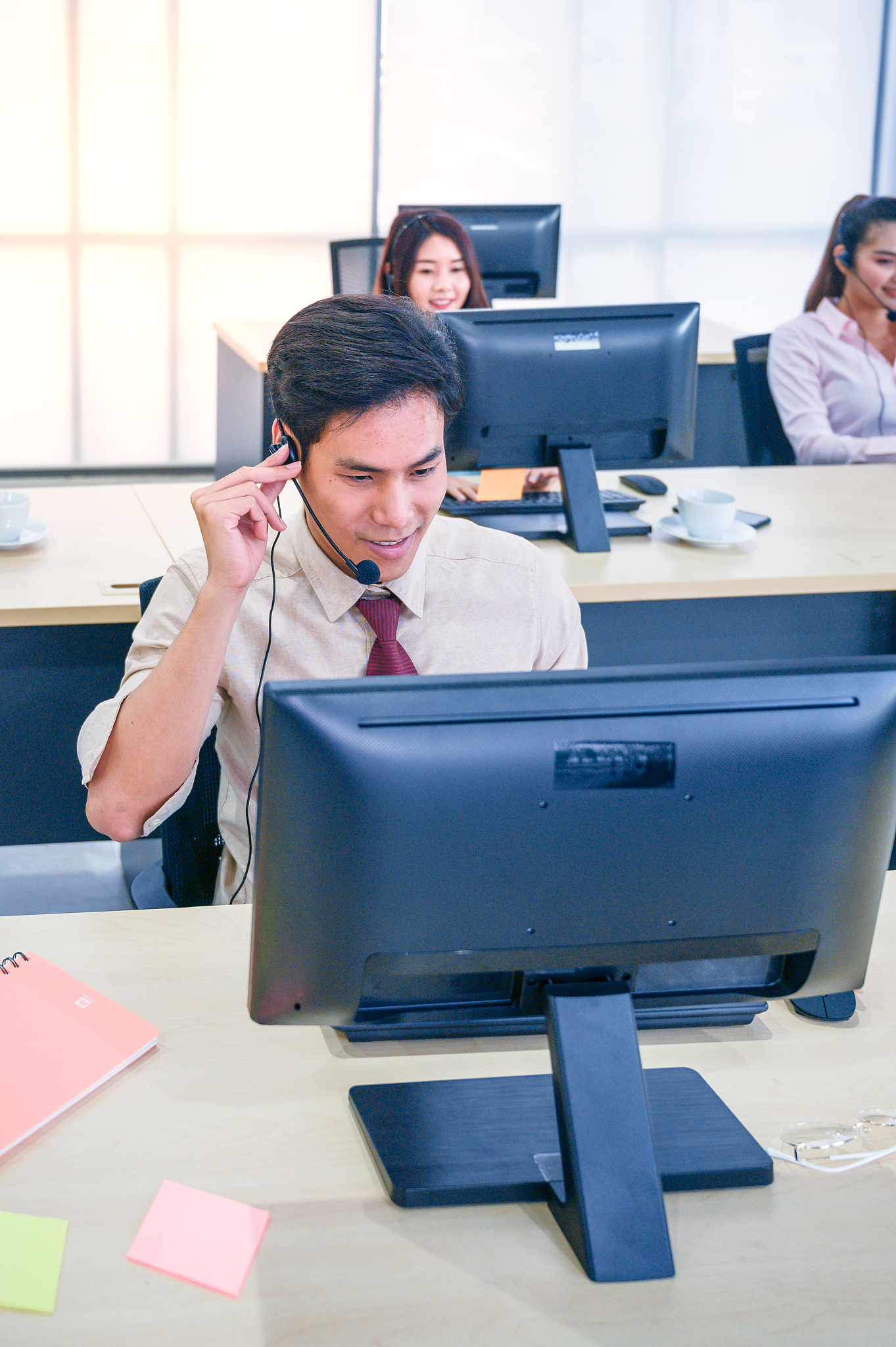 young customer service men agent with headsets and computer work