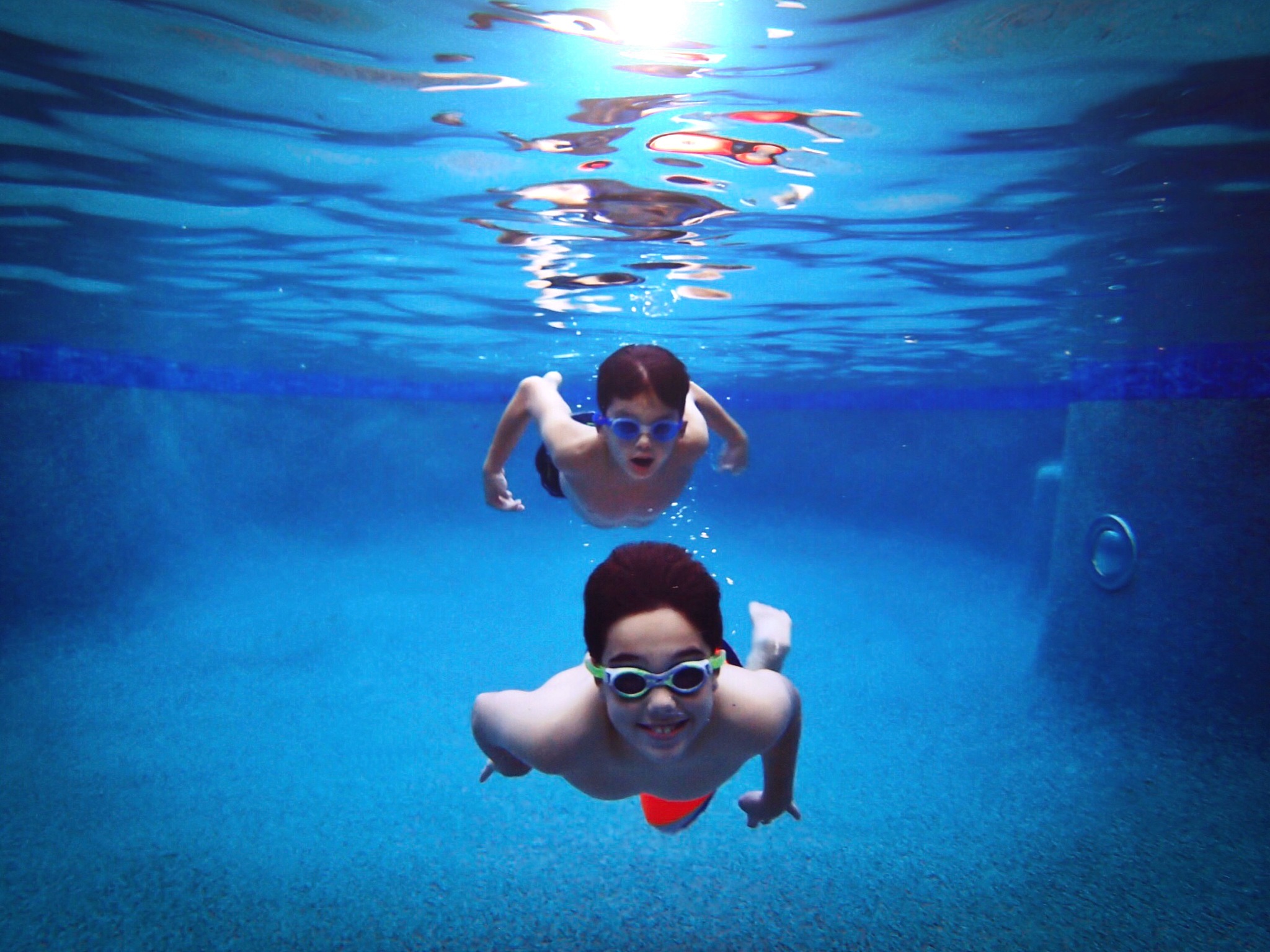 portrait of shirtless brothers swimming undersea