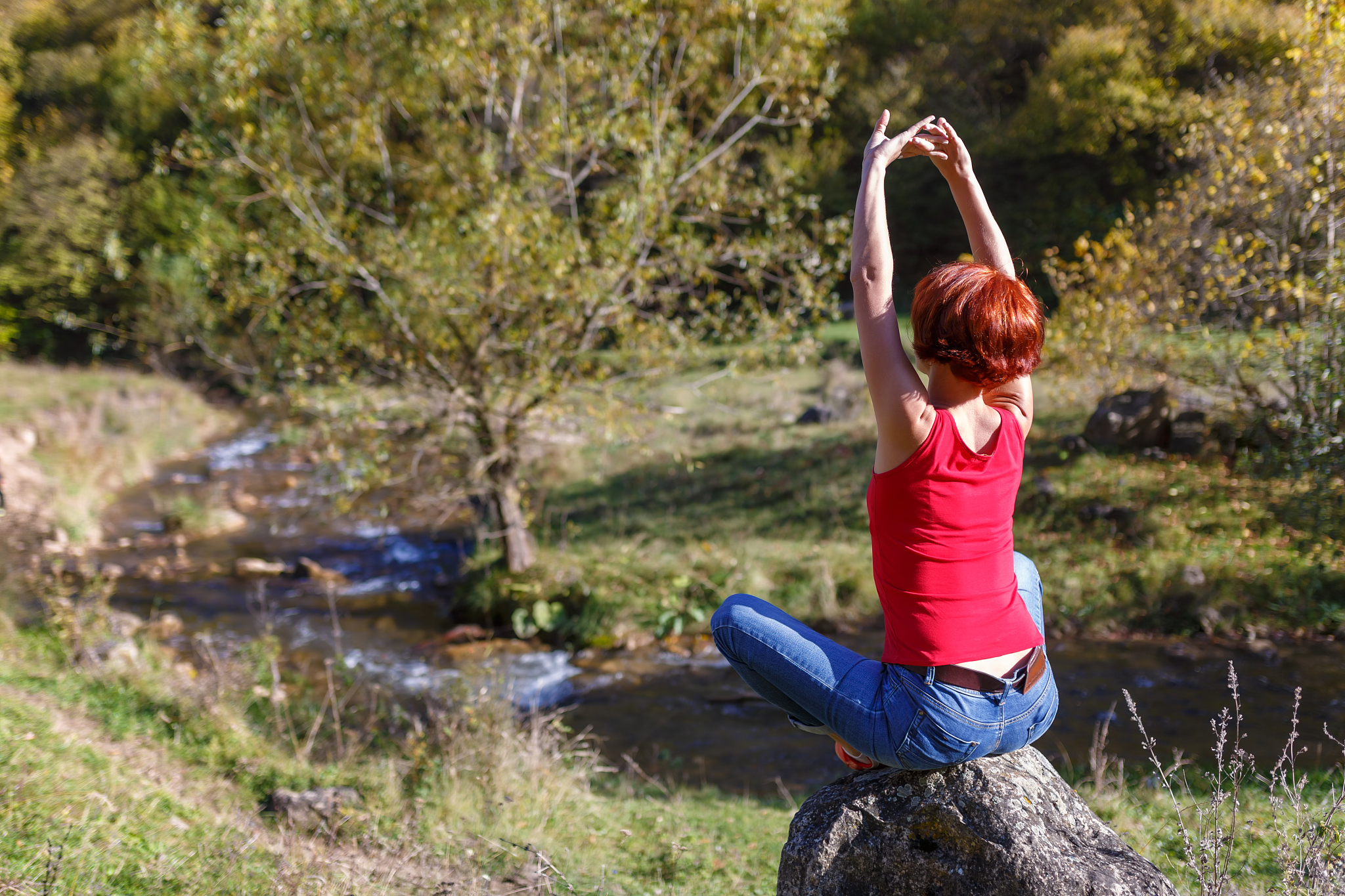 young woman sits on a stone and meditates against the background