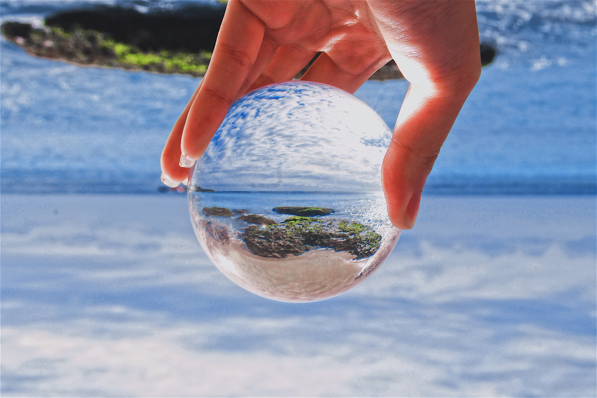 close-up of hand holding crystal ball at beach