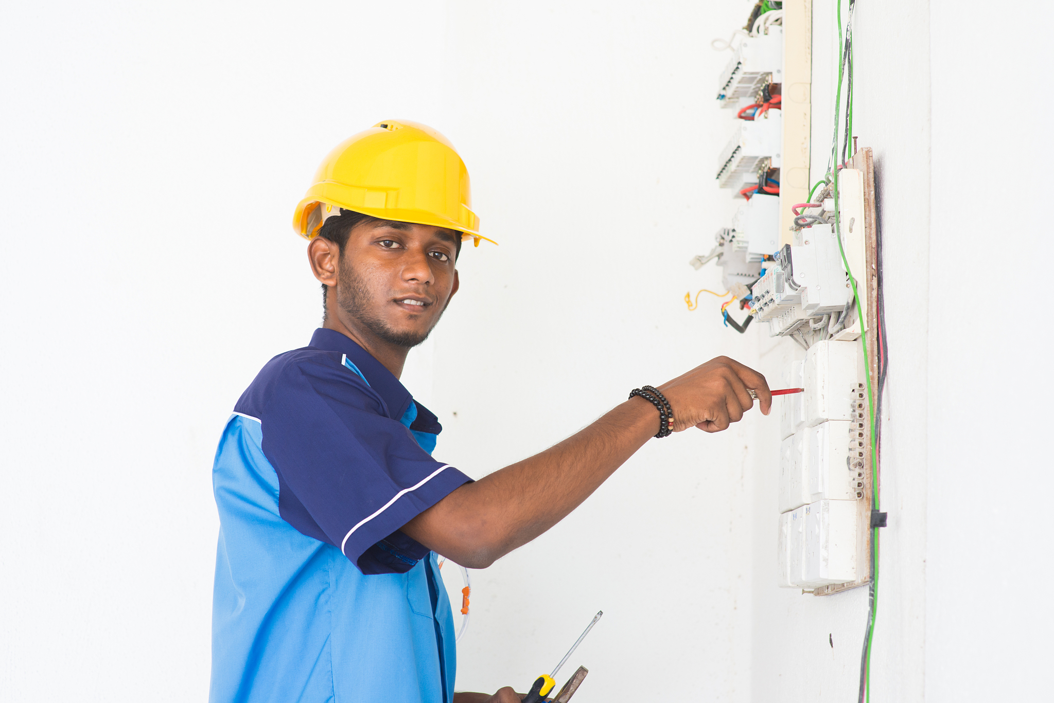 portrait of young man repairing electrical board on wall