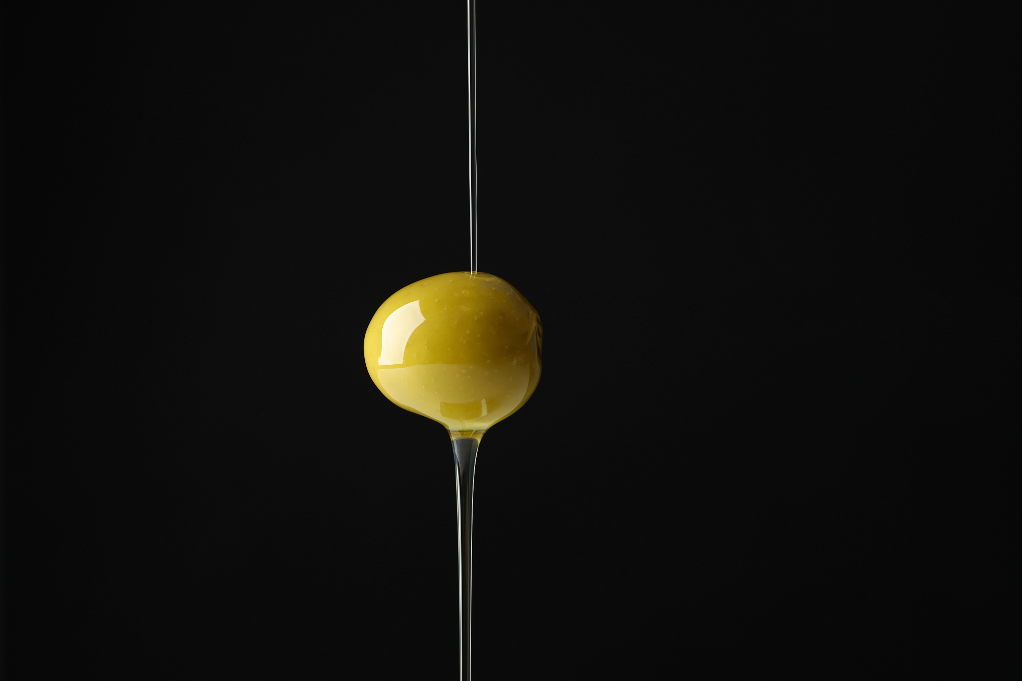 olive and pouring olive oil on black background, close up
