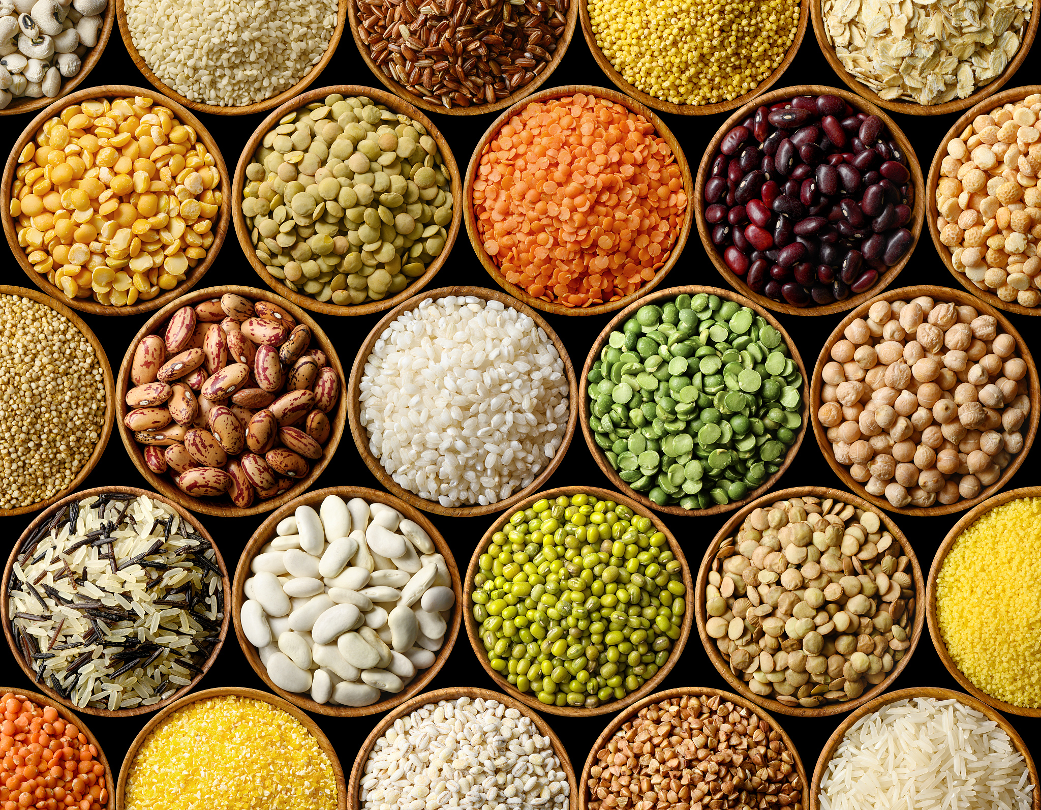 various colorful legumes and cereals on black background