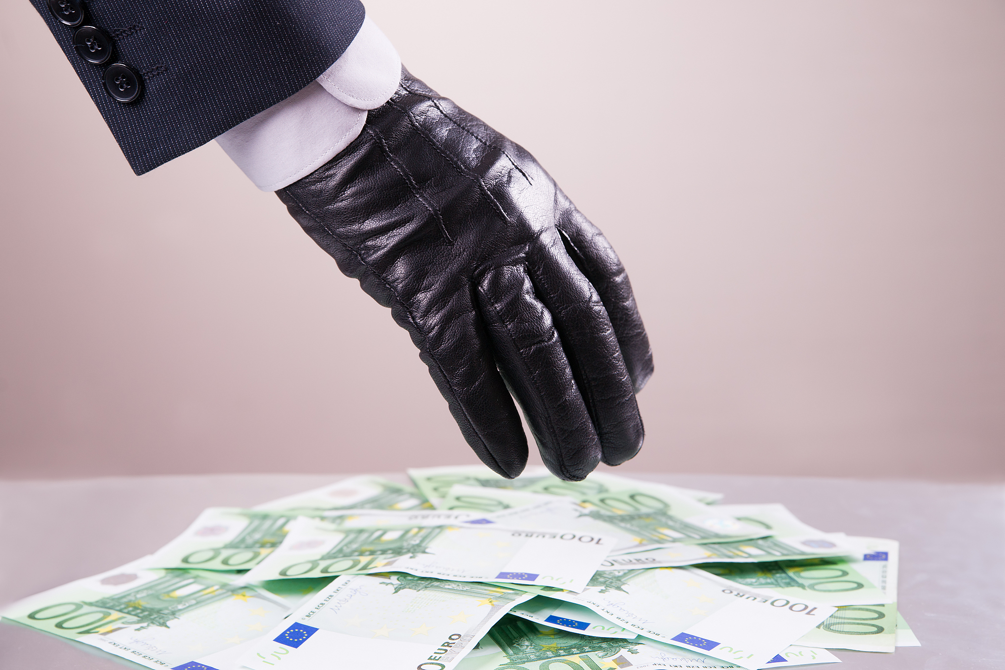hand in black glove steals money, bribe and corruption concept