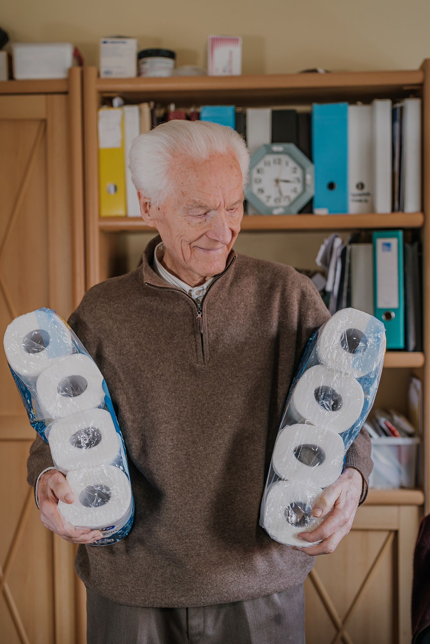 old man holding two packs of toilet paper