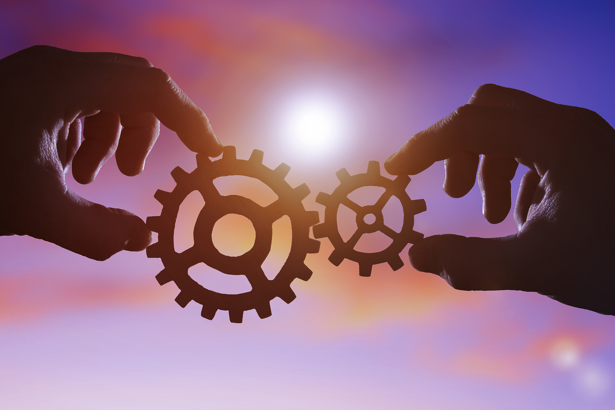 two gears in the hands of people at sunset.