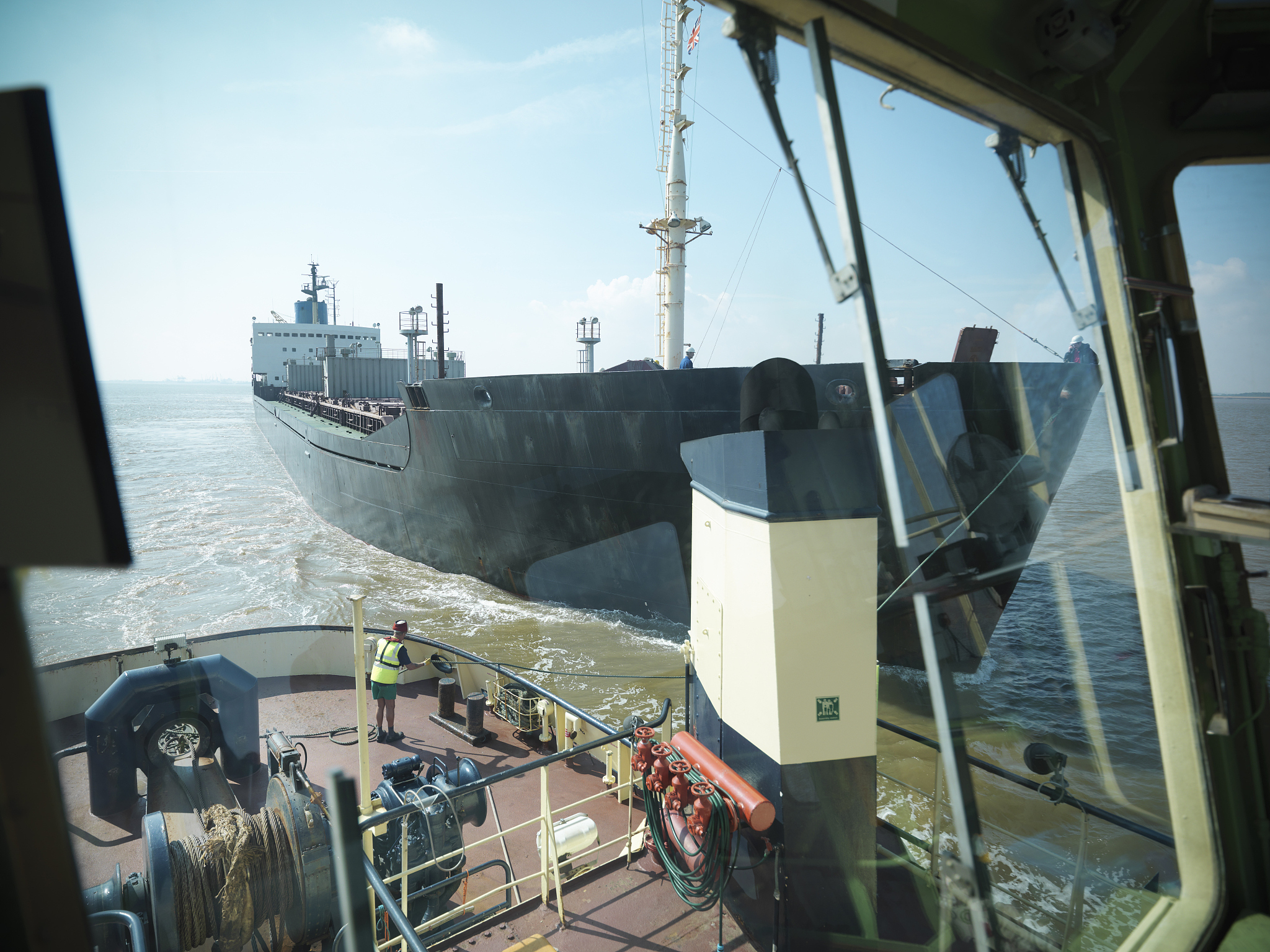 view from bridge of tugboat of sailor tyring tow lines to ship a