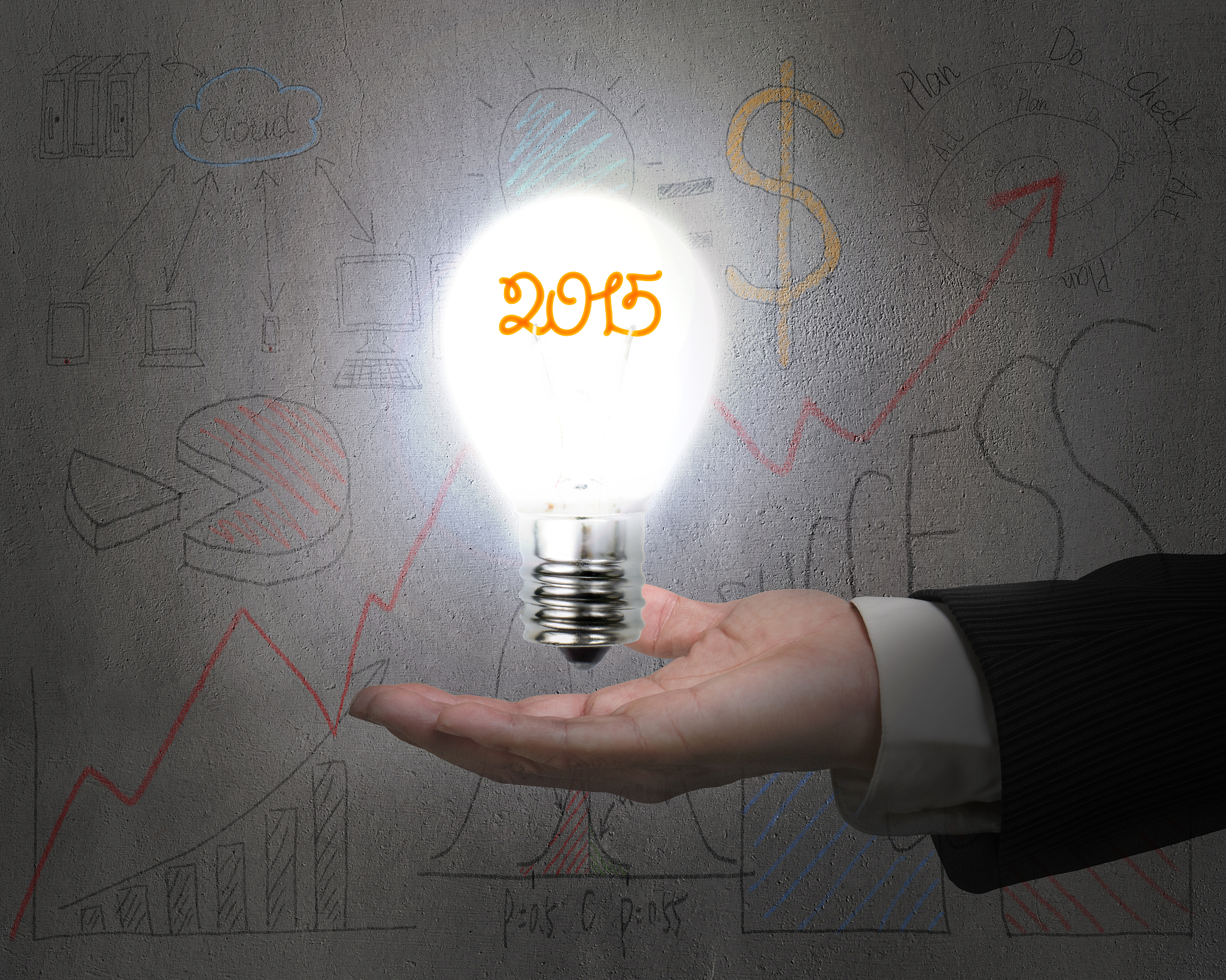 hand holding 2015 light bulb illuminated dark doodles wall