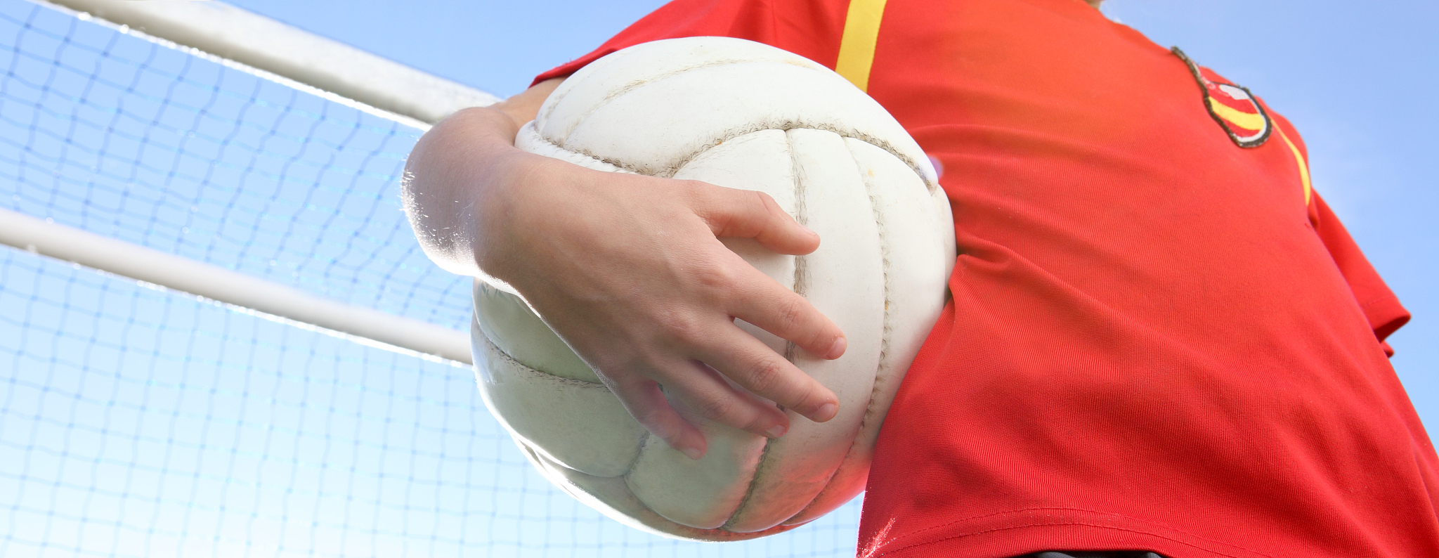 boy holding a football in front of a goal