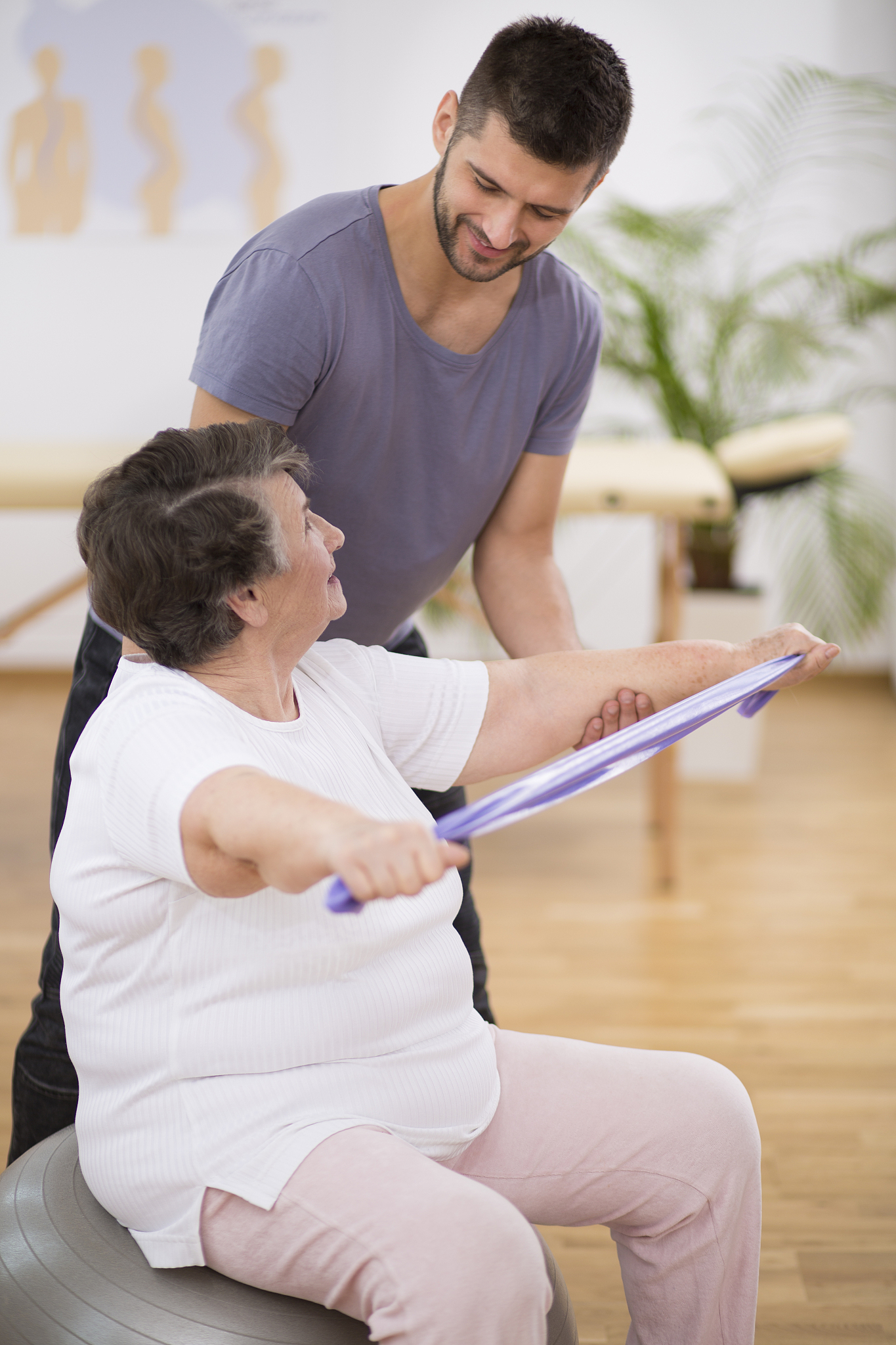 elderly pensioner exercising with resistance bands with her prof