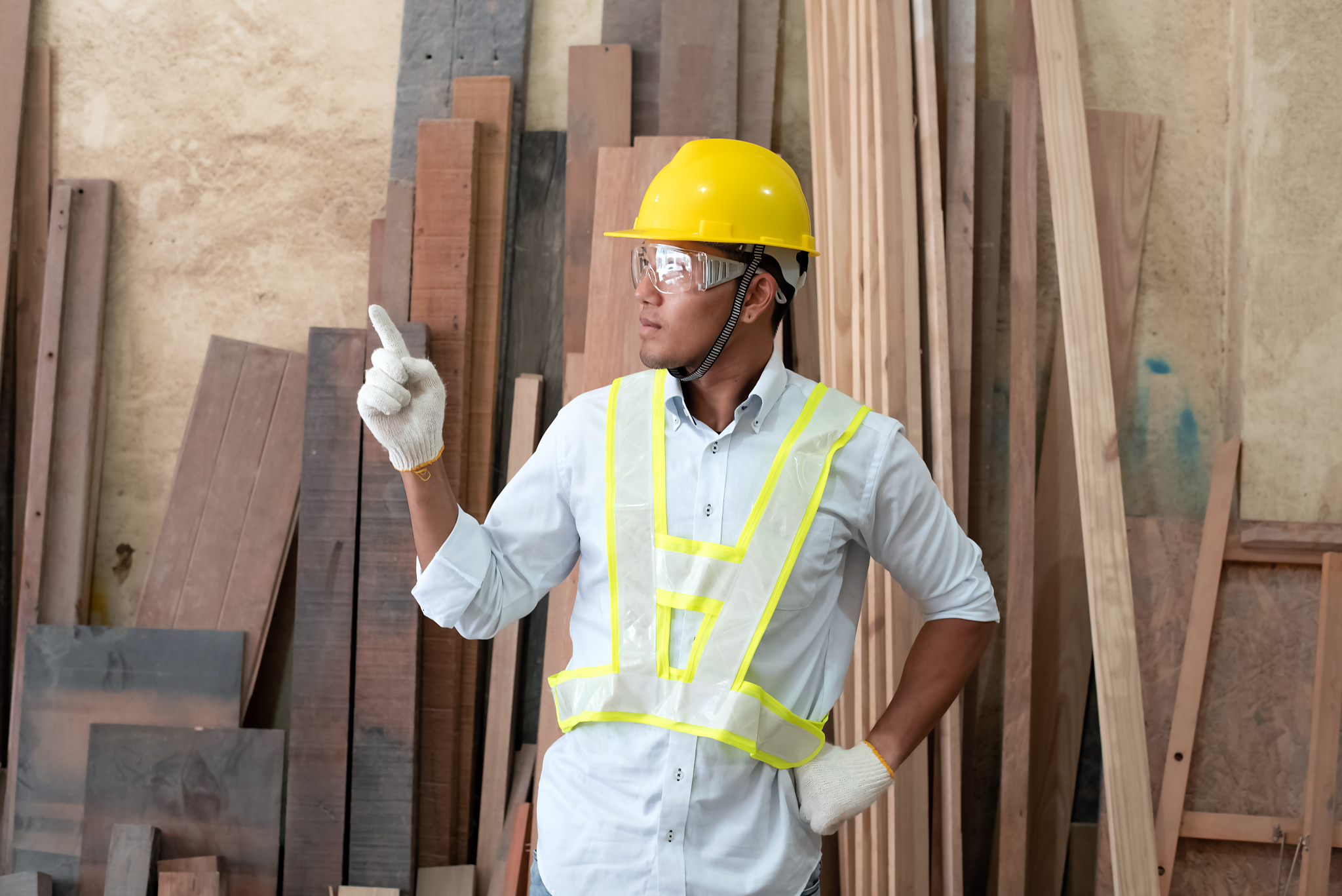 handsome man wearing protective glasses and yellow helmet,point 