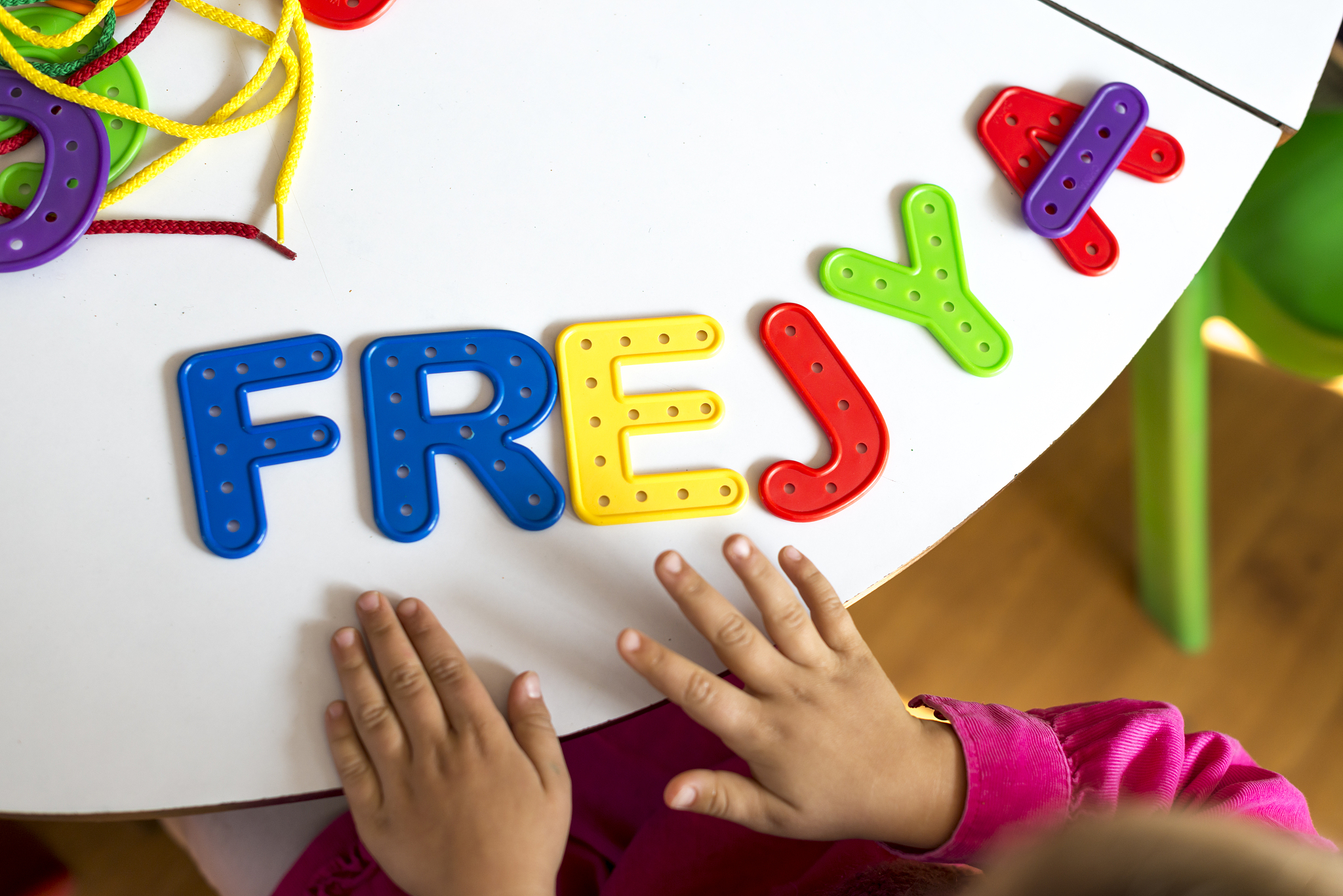 a child plays with colourful plastic letters in a classroom