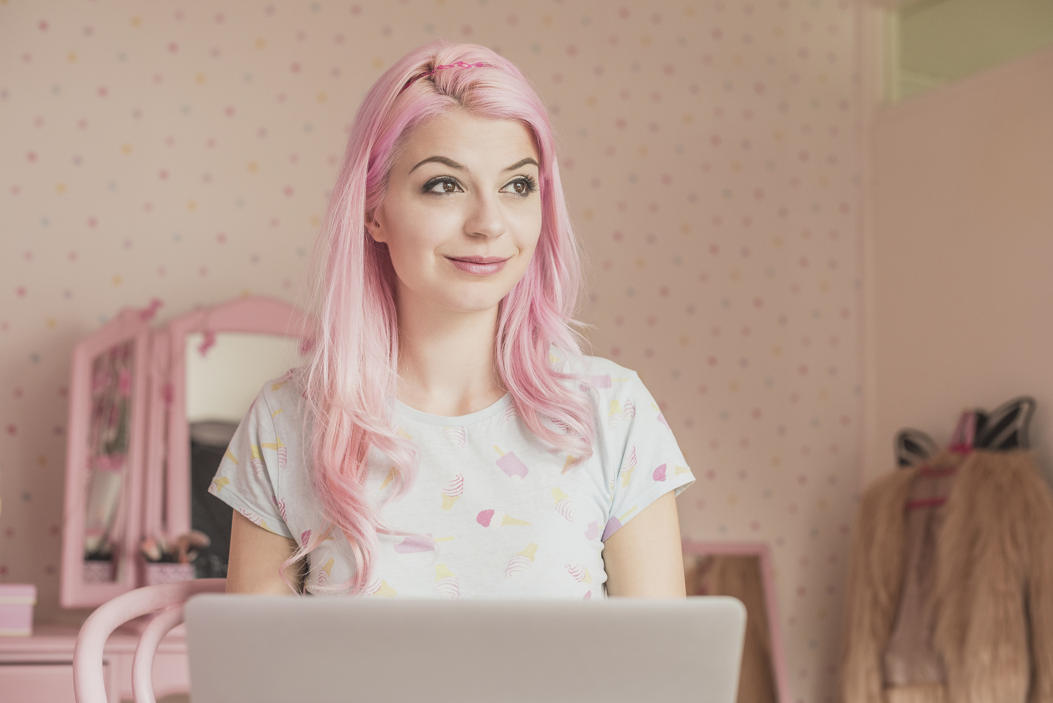 pensive young woman writing blog in laptop and looking away