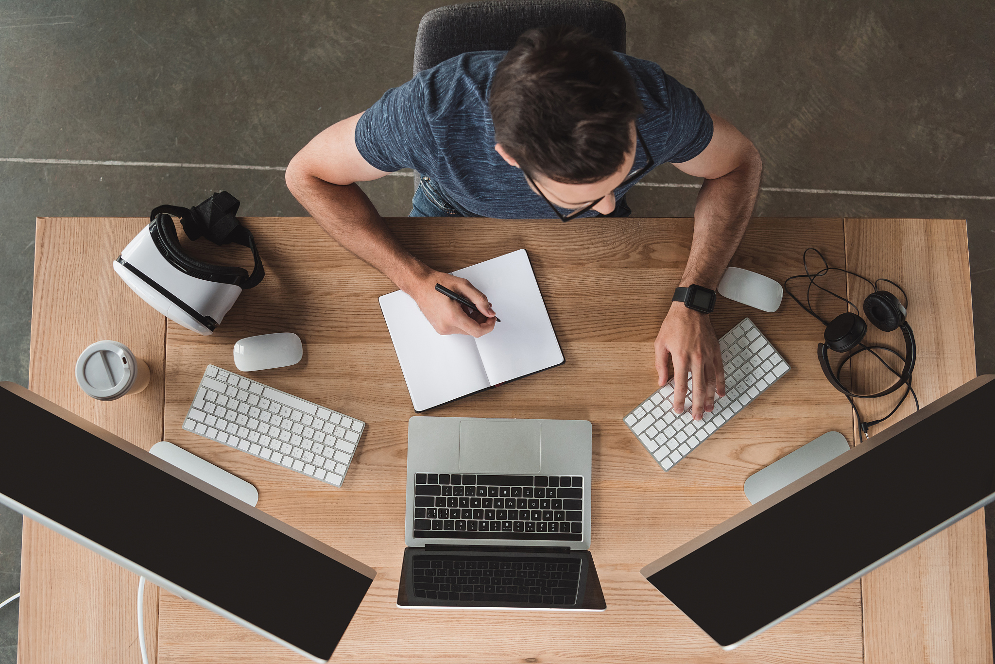 overhead view of young programmer taking notes in notebook and u