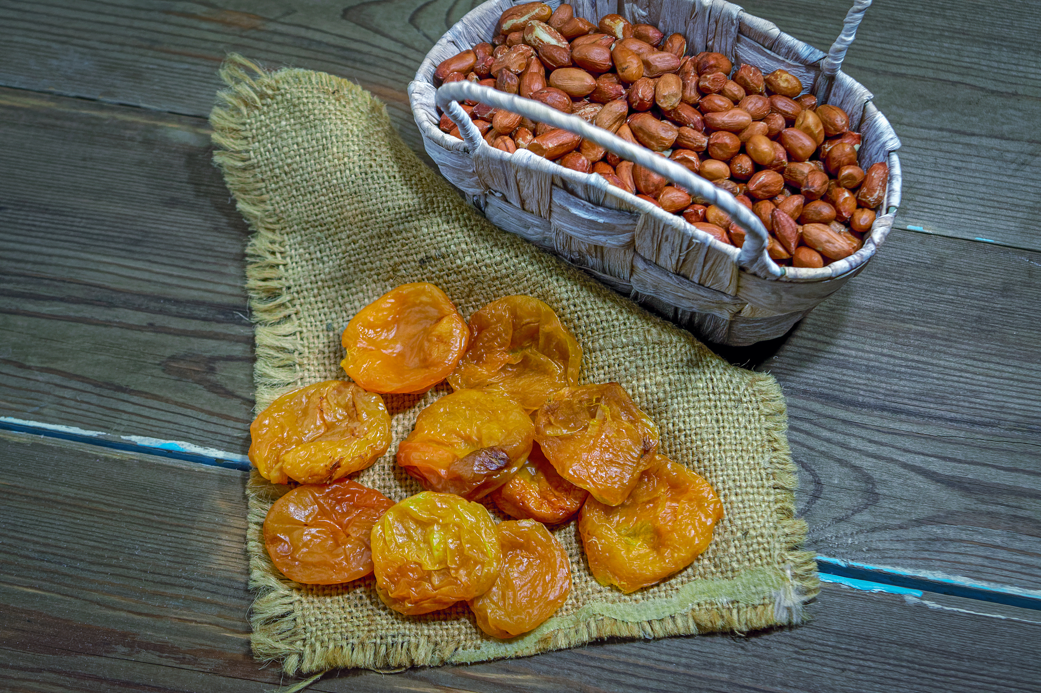 dried apricots and peanuts in a wicker basket on a wooden table