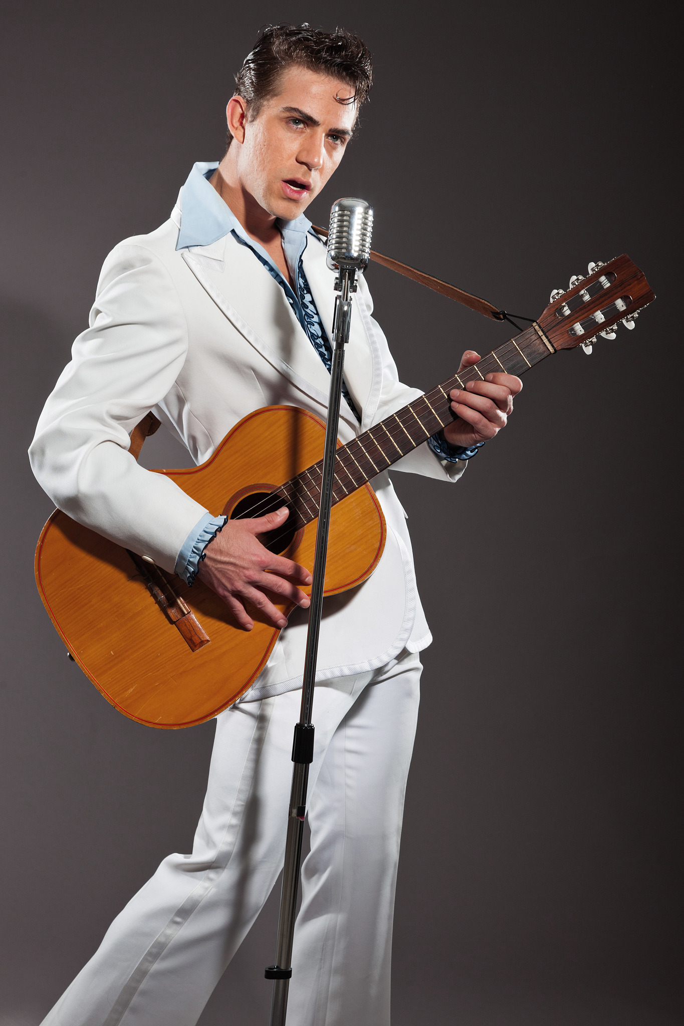 retro rock and roll singer with guitar wearing white suit.