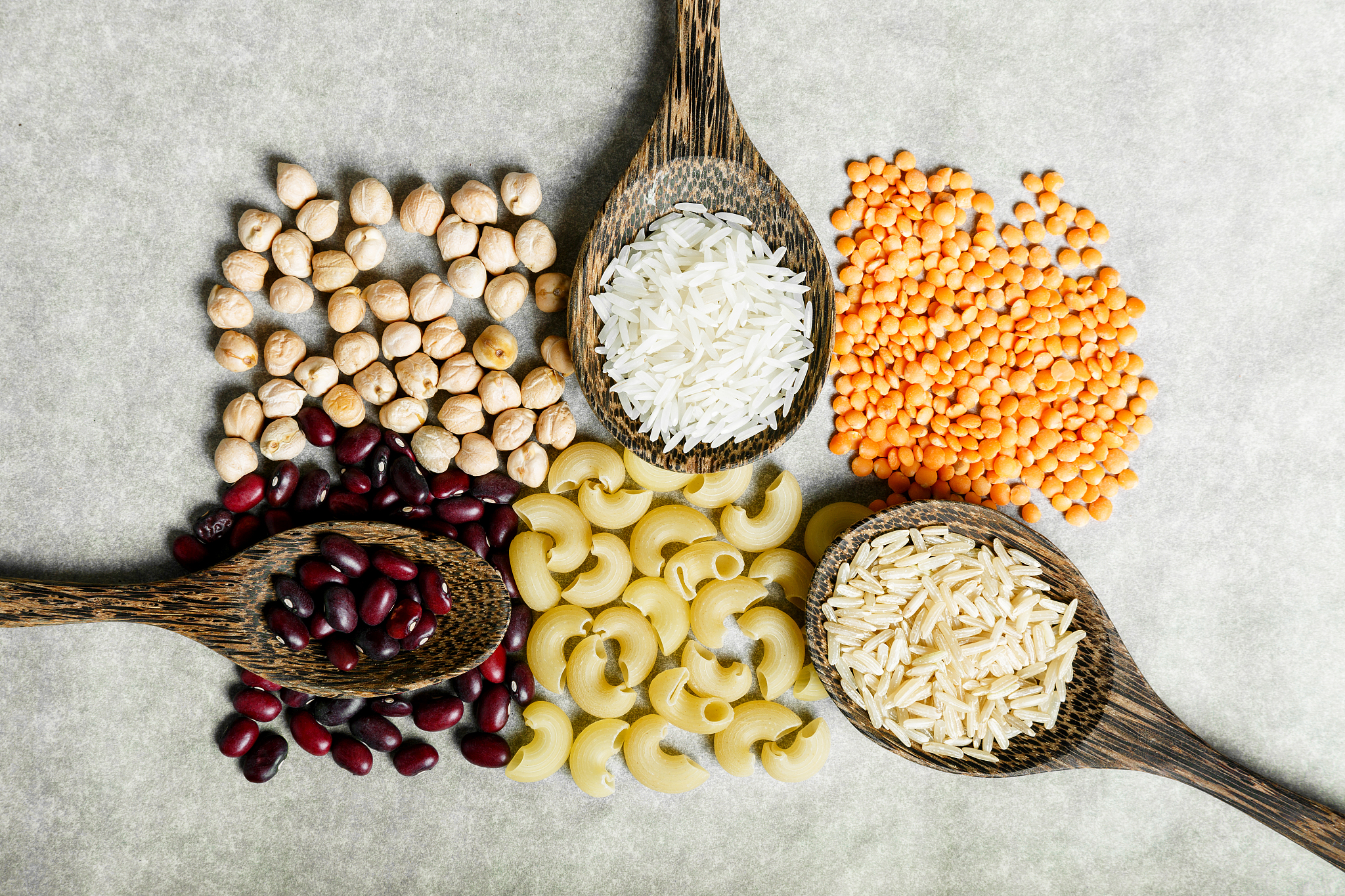 red lentils, white rice, beans, pasta and chickpeas in a wooden 