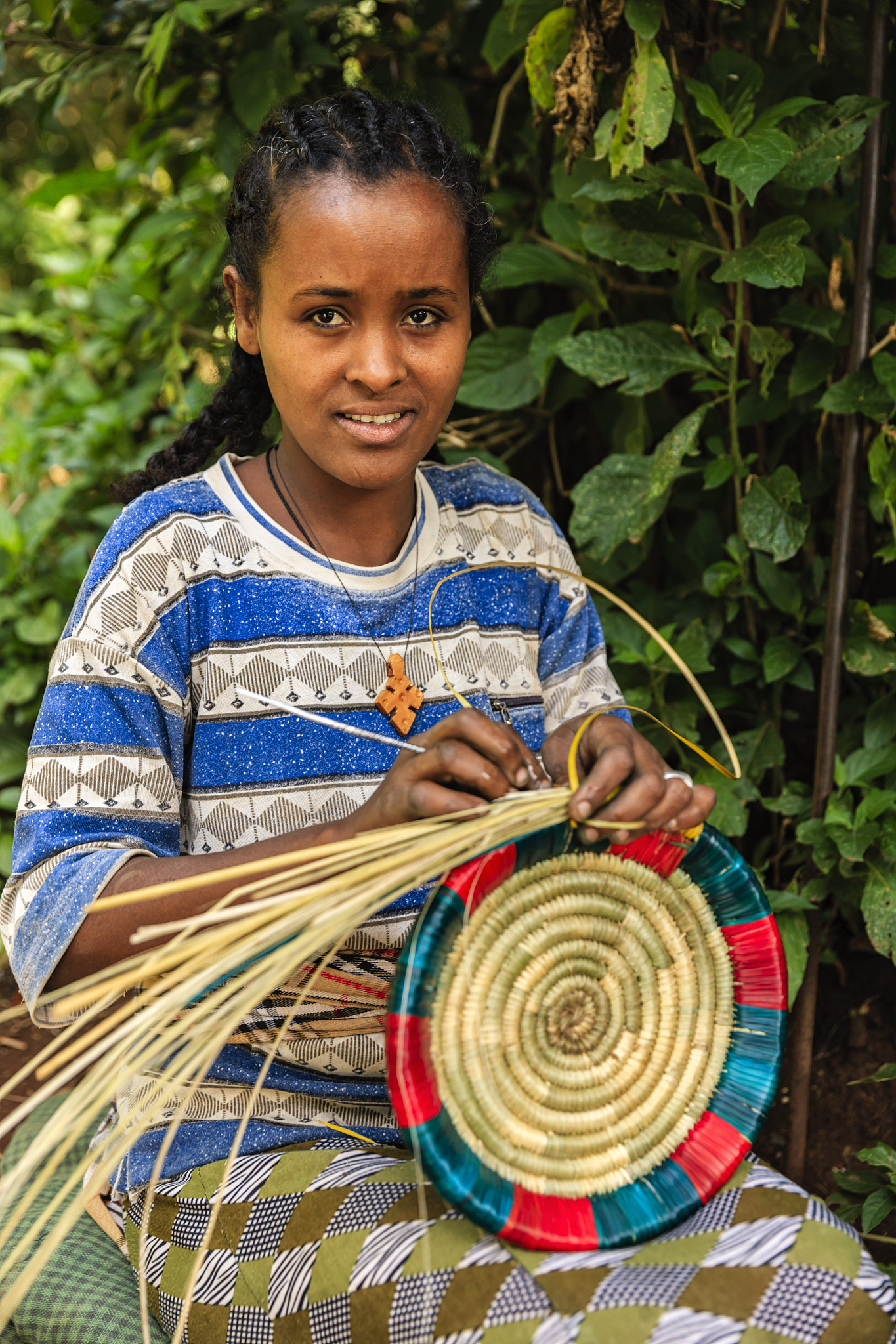 young african woman weaving food basket in ethiopia, east africa