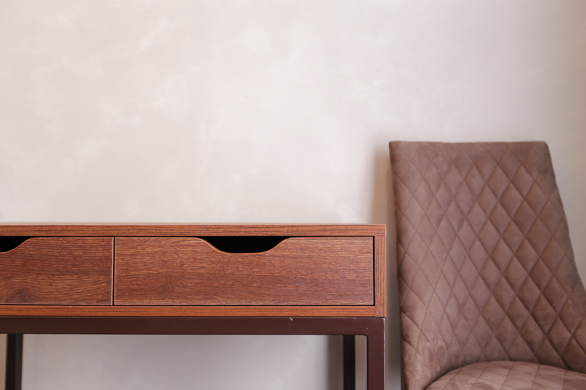 modern wooden table with arm chair against grey wall close up