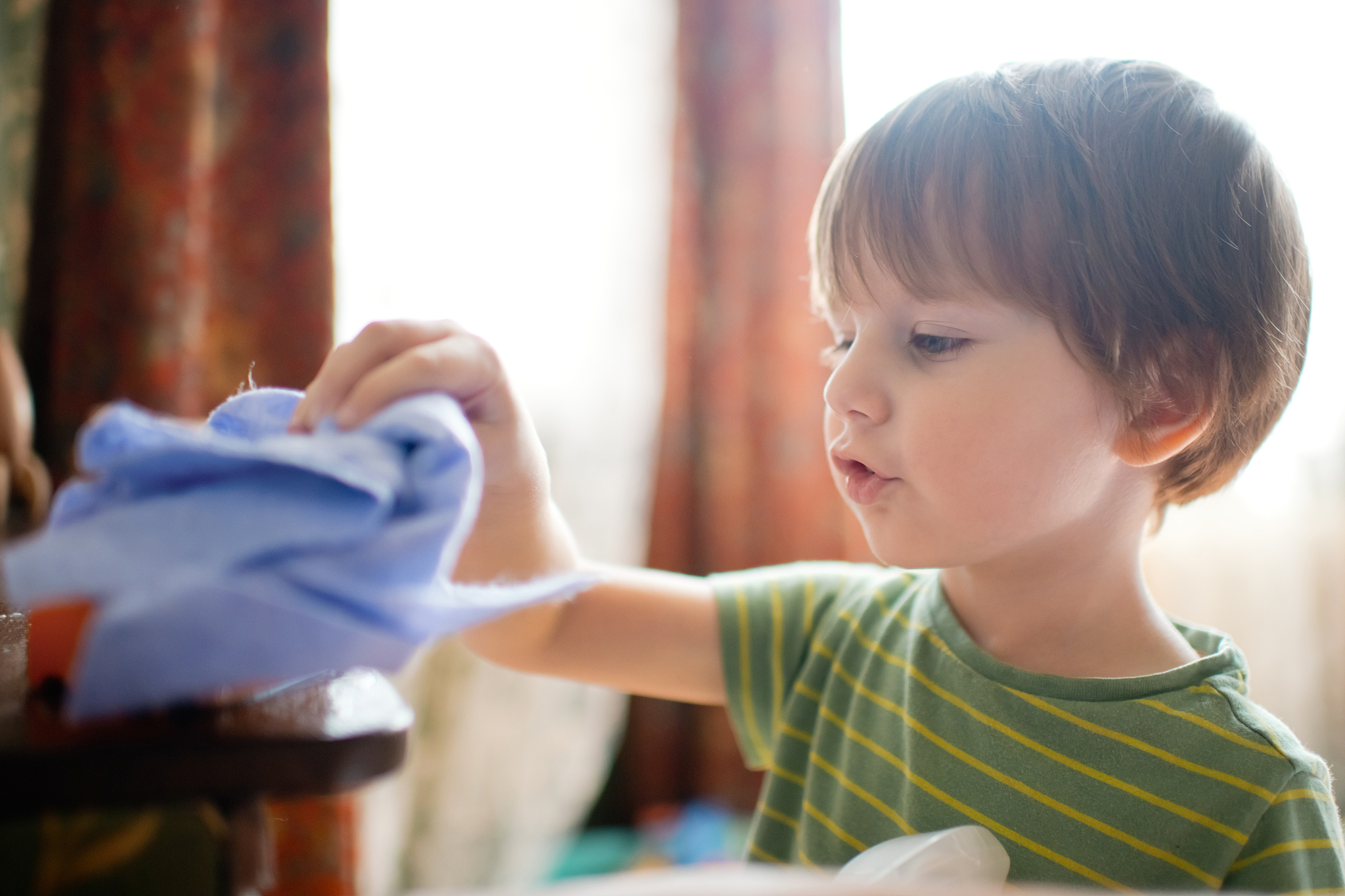 little boy cleaning his toys at home