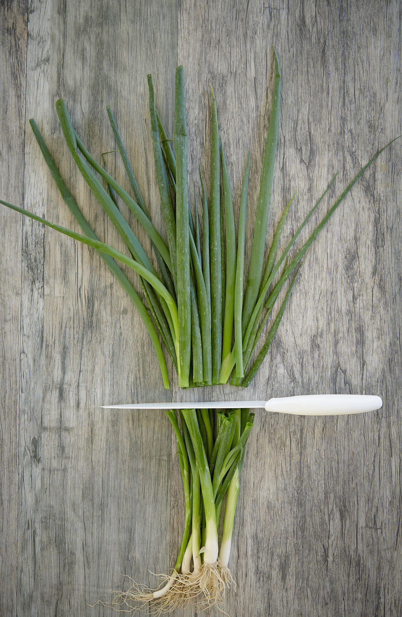 spring onions being cut on wooden table