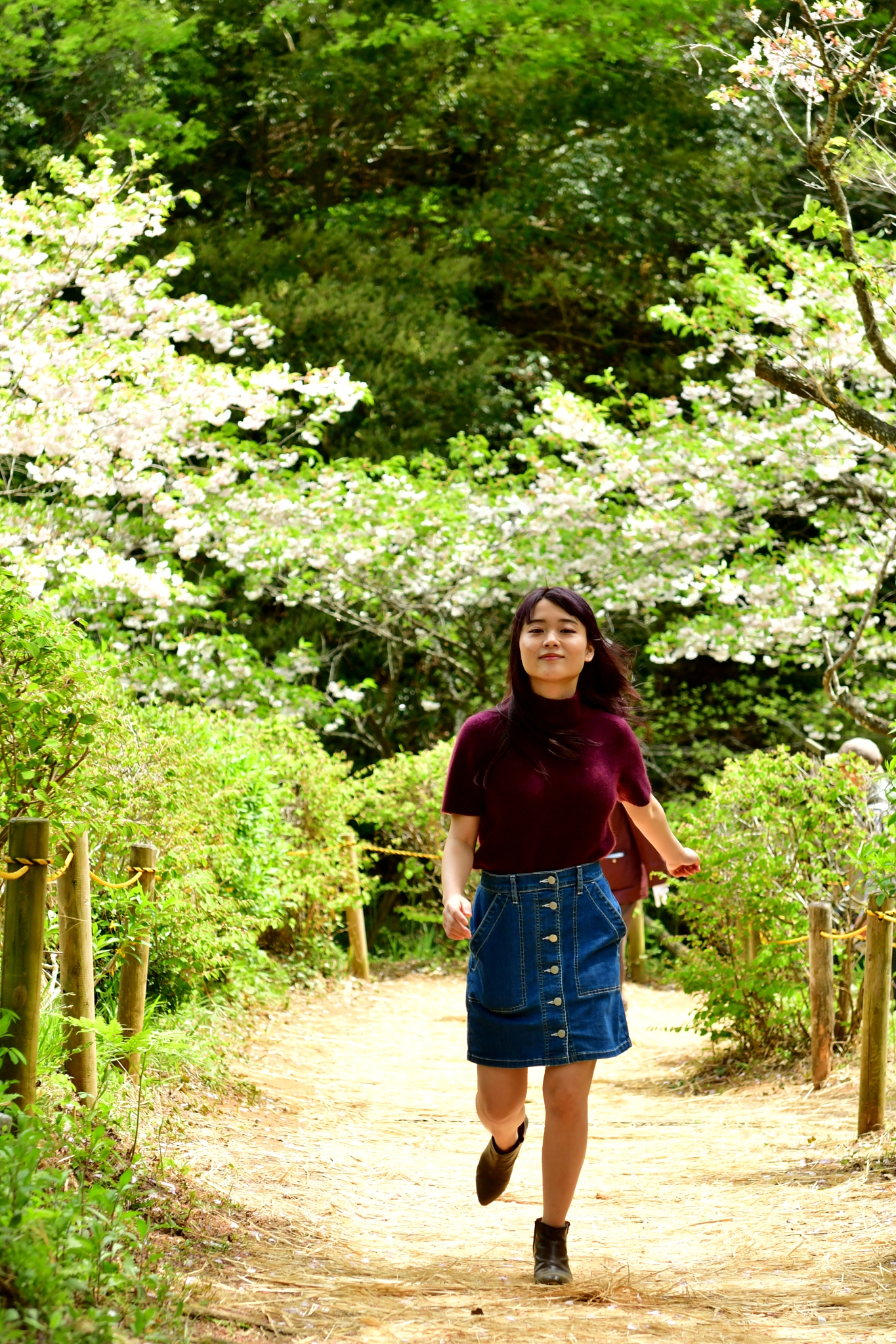 young japanese woman walking in forest with cherry blossom behin