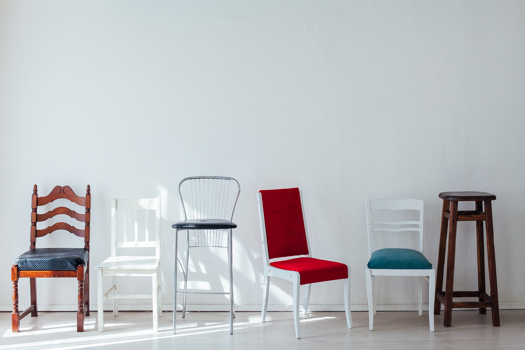 many different chairs of different colors stand at the white wal