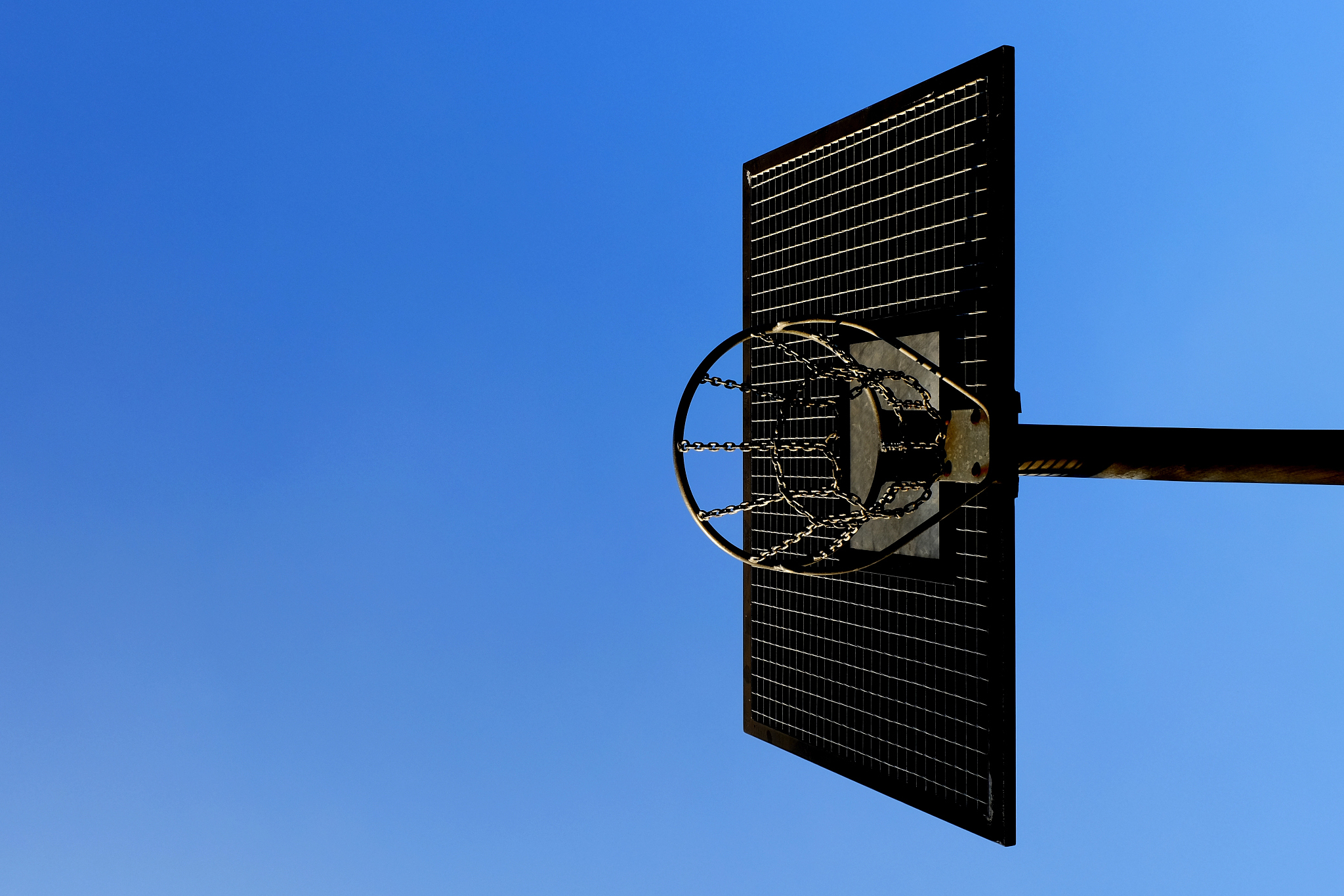 directly below shot of basketball hoop against clear blue sky on