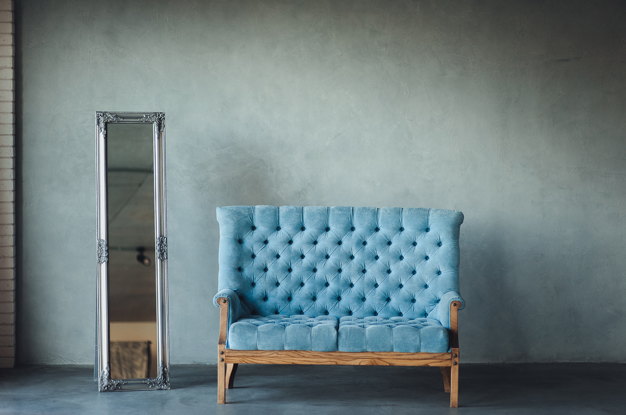 a blue fabric sofa and antique mirror with a frame stand on a gr