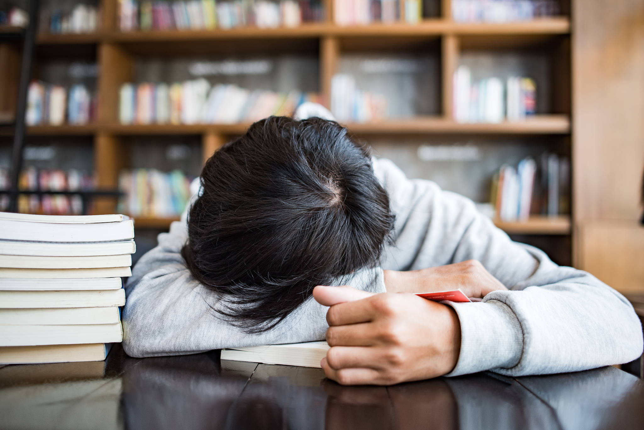 sleeping bearded young man student lies on hands in cafe