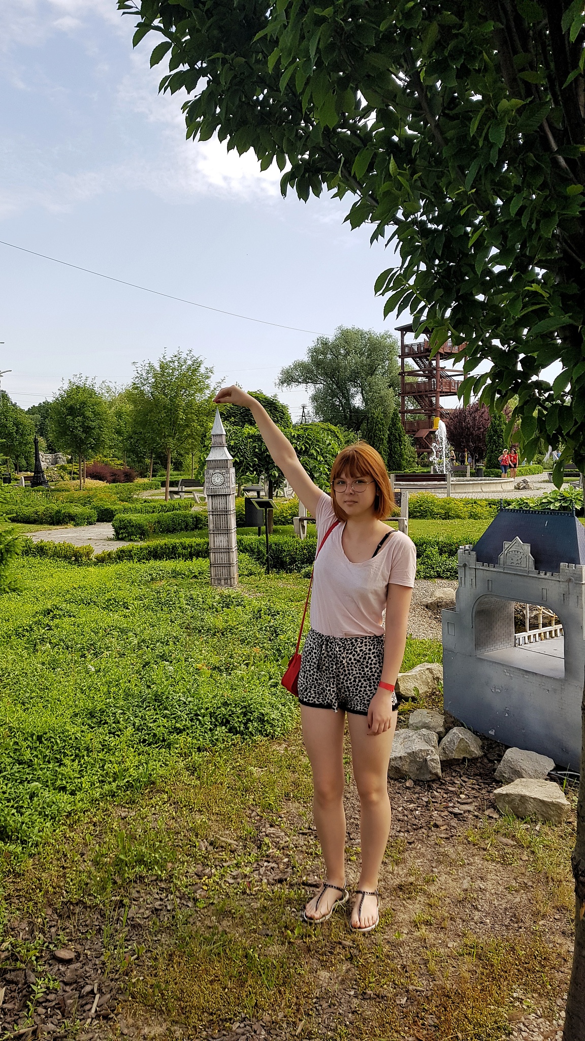 portrait of teenage boy gesturing against tower in garden